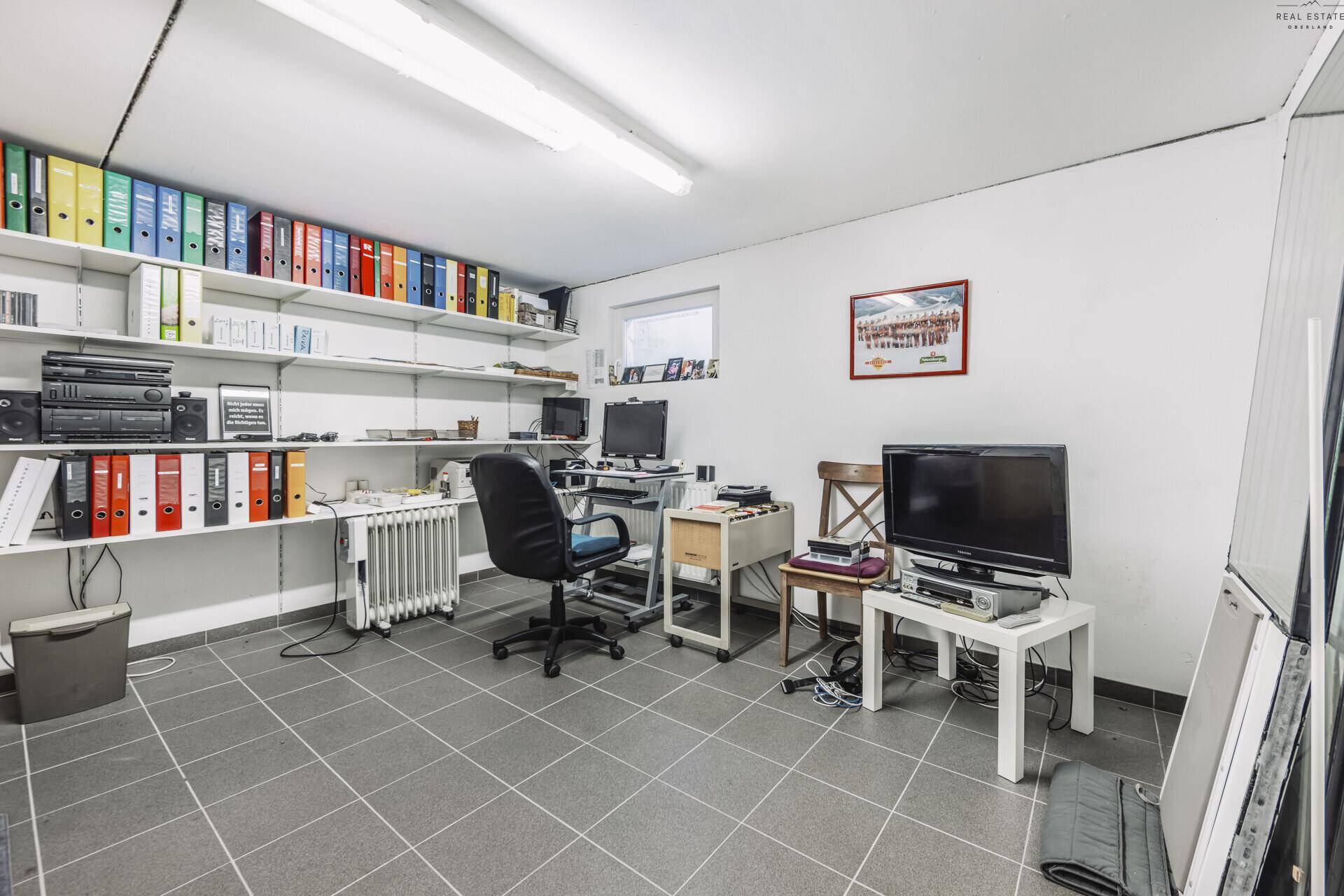 Geräumiger Hobbyraum oder Büro im Kellergeschoss mit Regalen und Arbeitsplatz.