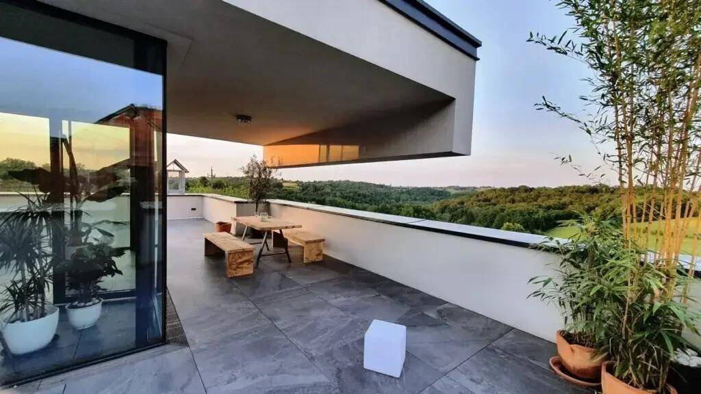 Geräumige Außenterrasse mit Holzmöbeln und weitem Blick über eine grüne Landschaft, ideal zum Entspannen.
