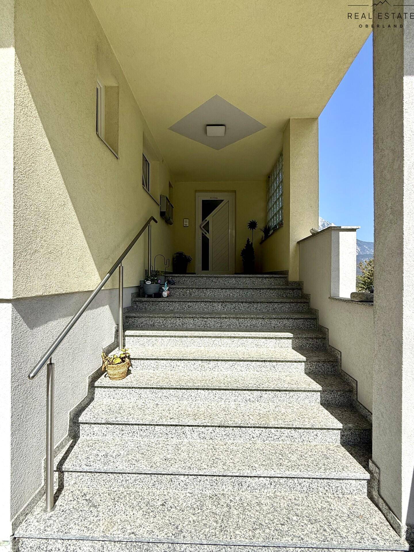 Außentreppe mit Granitstufen und Handlauf führt zum überdachten Eingangsbereich des Hauses.