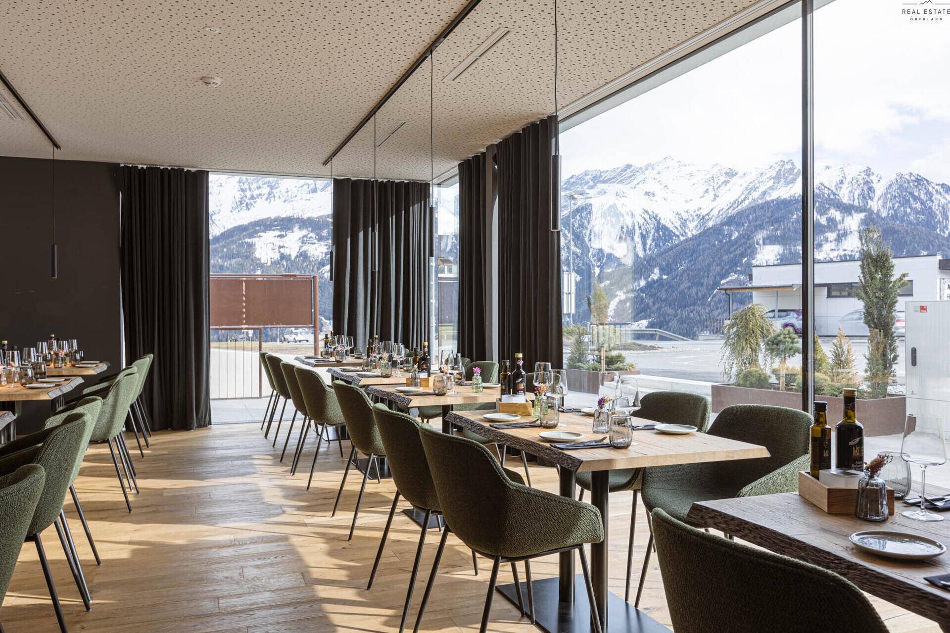 Heller Essbereich mit großen Fenstern, die einen beeindruckenden Bergblick bieten, und modern gedeckten Tischen.