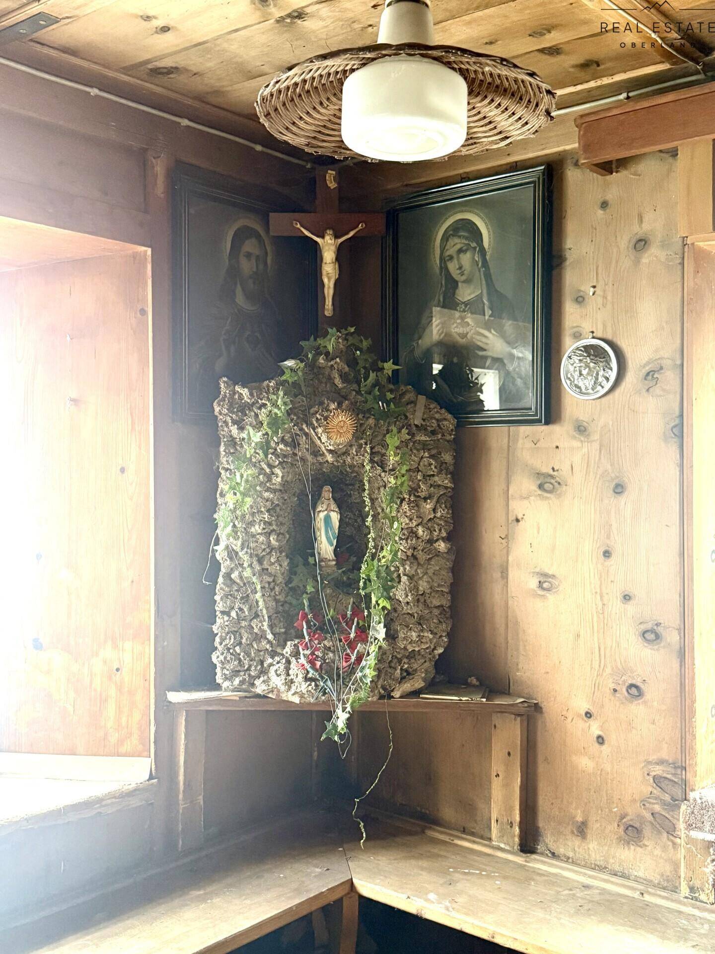 Ecke eines traditionellen Wohnzimmers mit Holztäfelung und religiösen Dekorationen.