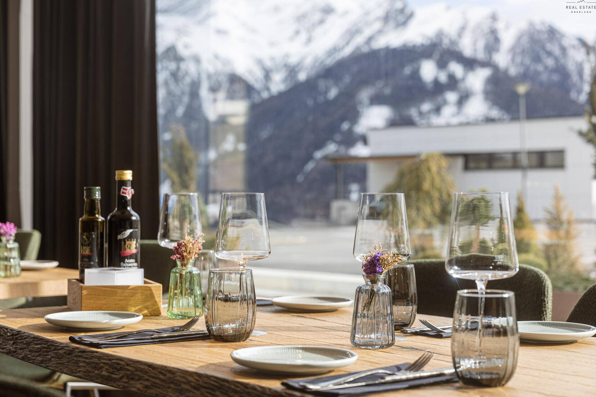 Nahaufnahme eines gedeckten Tisches mit Blick auf die majestätischen Berge durch das große Fenster, schafft eine besondere Atmosphäre.