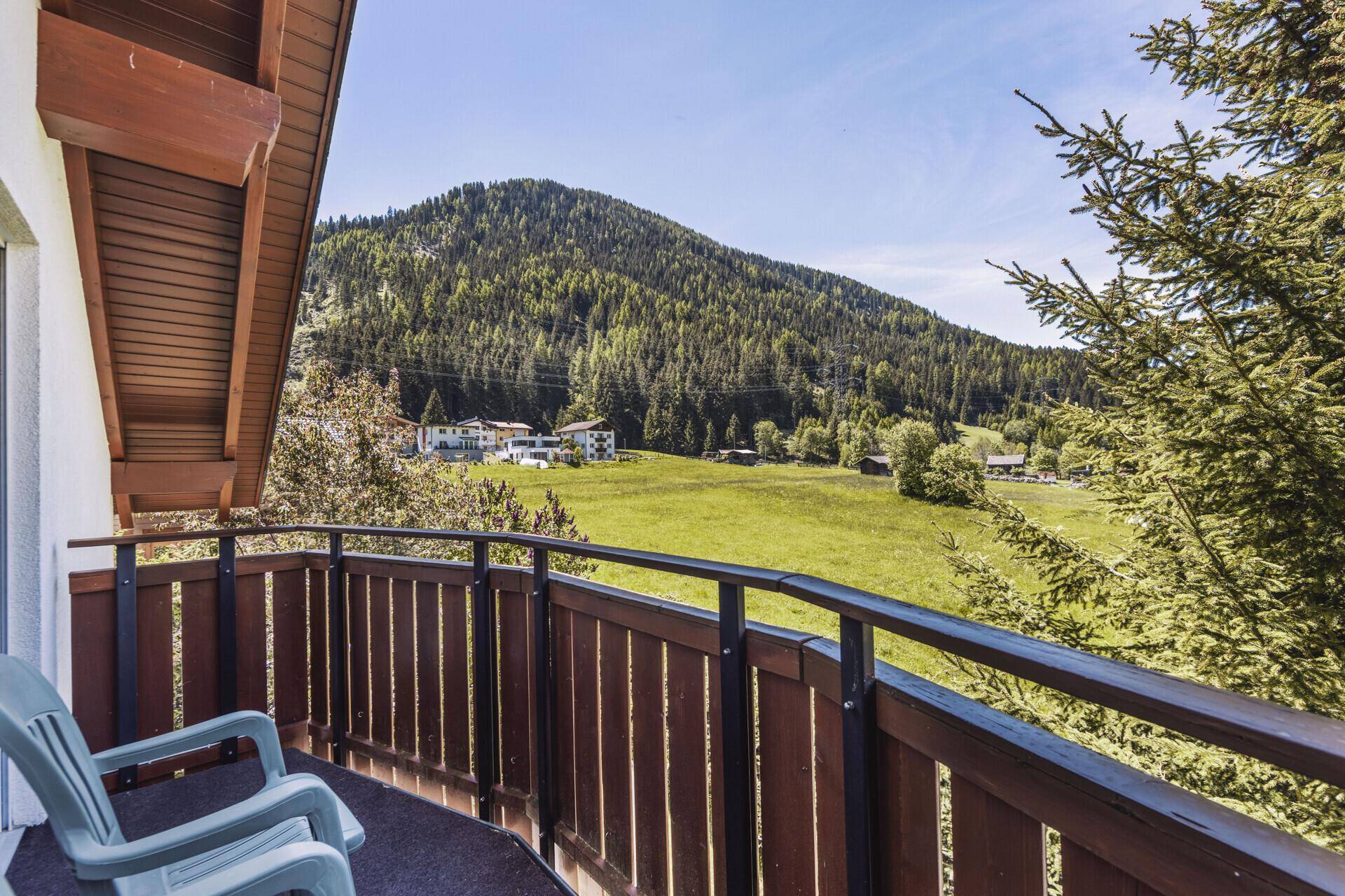 Balkon mit Blick auf grüne Wälder und die umliegende Berglandschaft unter blauem Himmel.