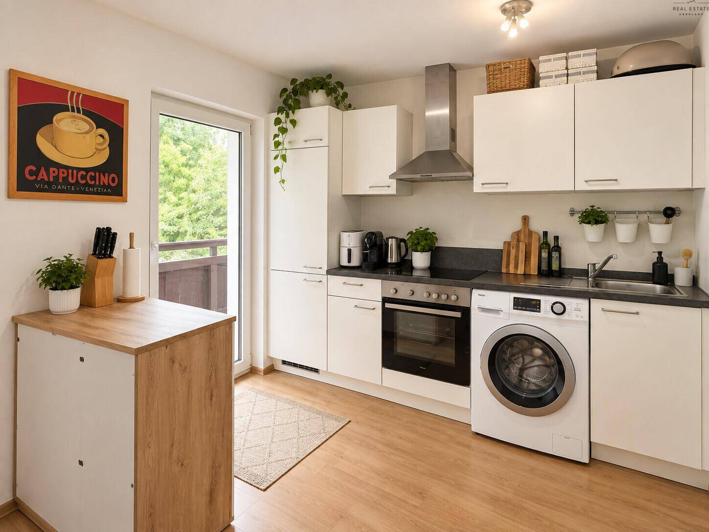 Moderne Küche mit weißen Schränken, integrierter Waschmaschine und Zugang zum Balkon.