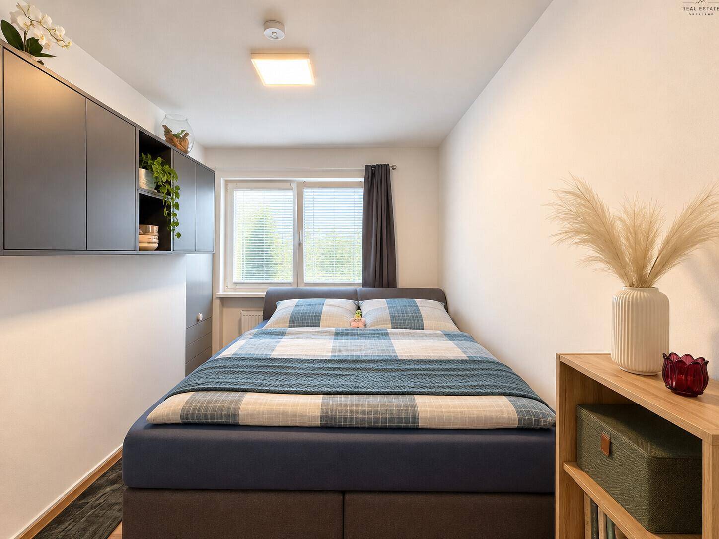 Gemütliches Schlafzimmer mit Doppelbett, schwebenden Schränken und Fenster mit Blick ins Grüne.