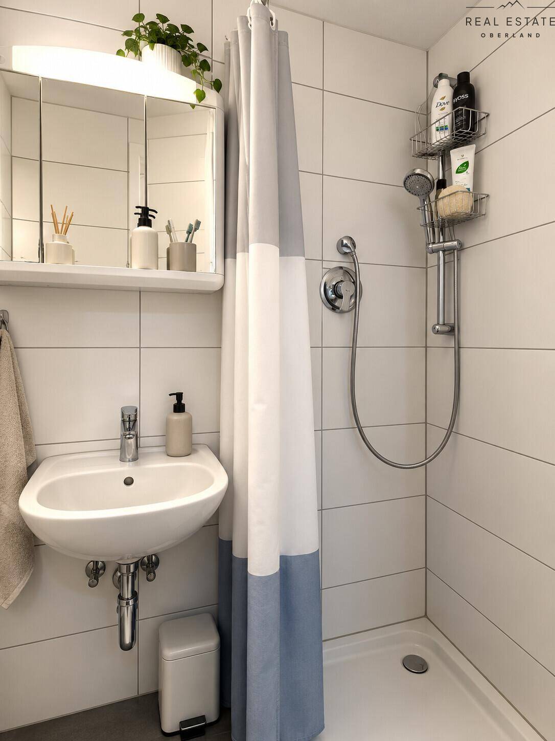 Kleines Badezimmer mit Dusche, Waschbecken und weißen Fliesen.