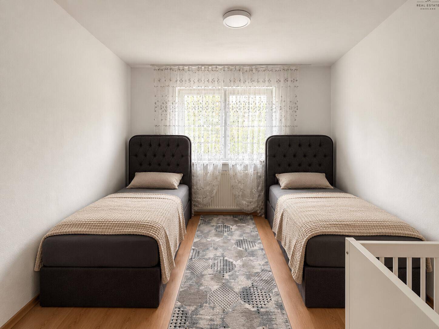 Kinderzimmer mit zwei Einzelbetten, Teppich und Fenster mit hellen Vorhängen.