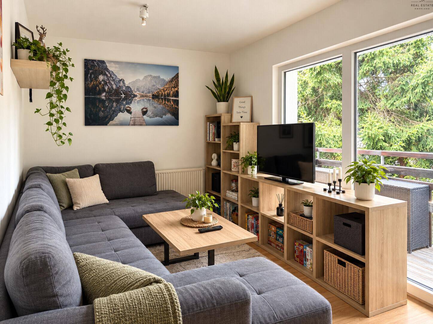 Heller Wohnbereich mit großem Ecksofa, Bücherregalen und Zugang zum Balkon.