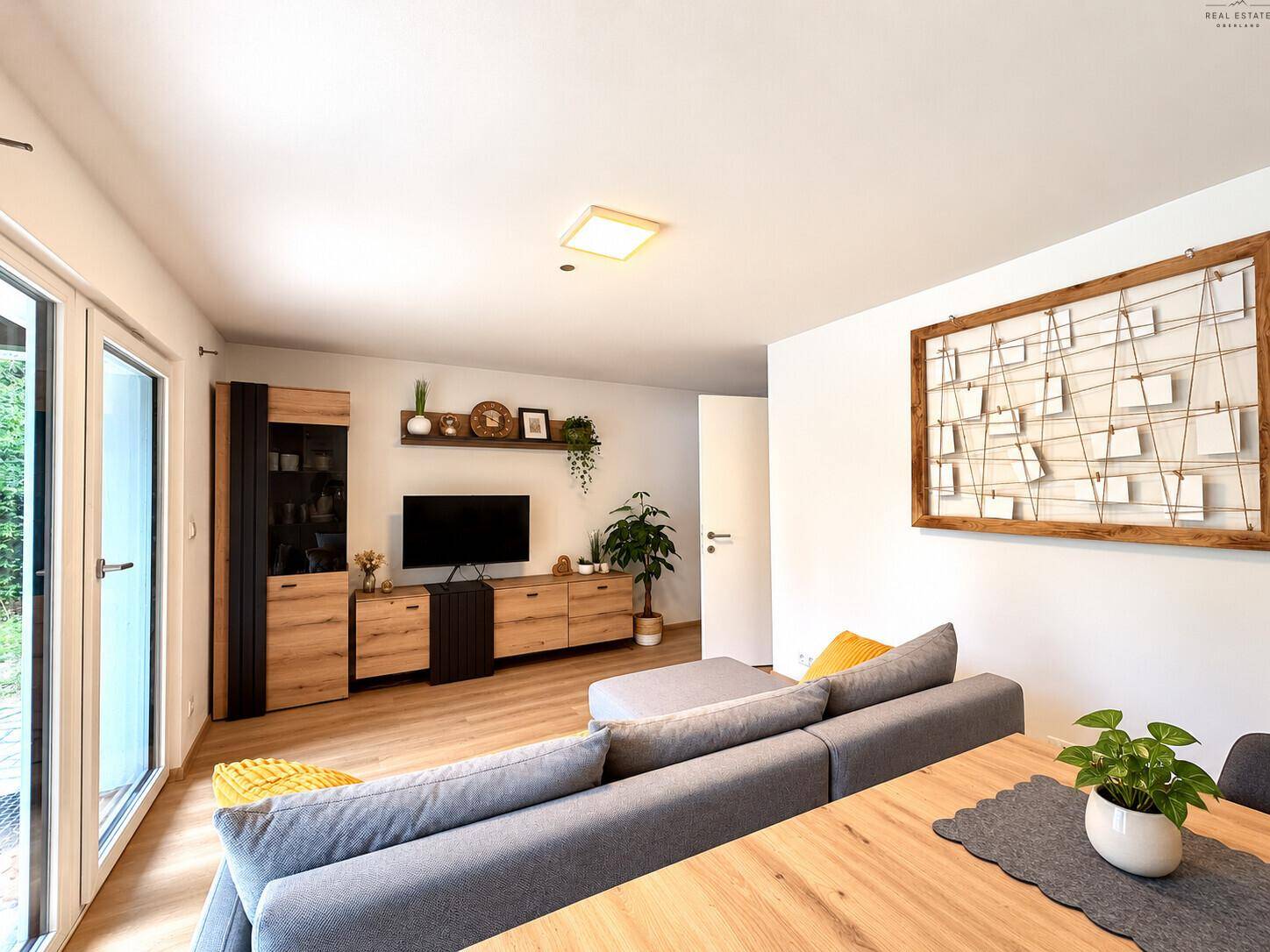Geräumiger Wohnbereich mit moderner Einrichtung, großem Sofa und Blick in den Garten.