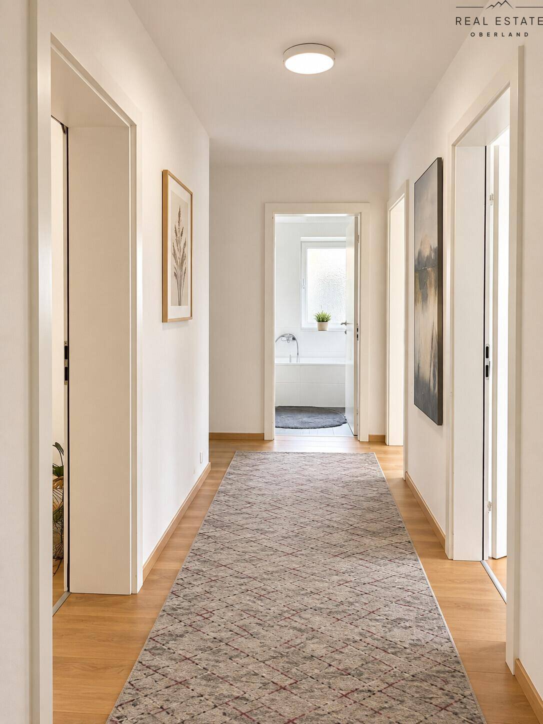 Heller Flur mit Holzboden, Teppichläufer und Türen zu verschiedenen Räumen.
