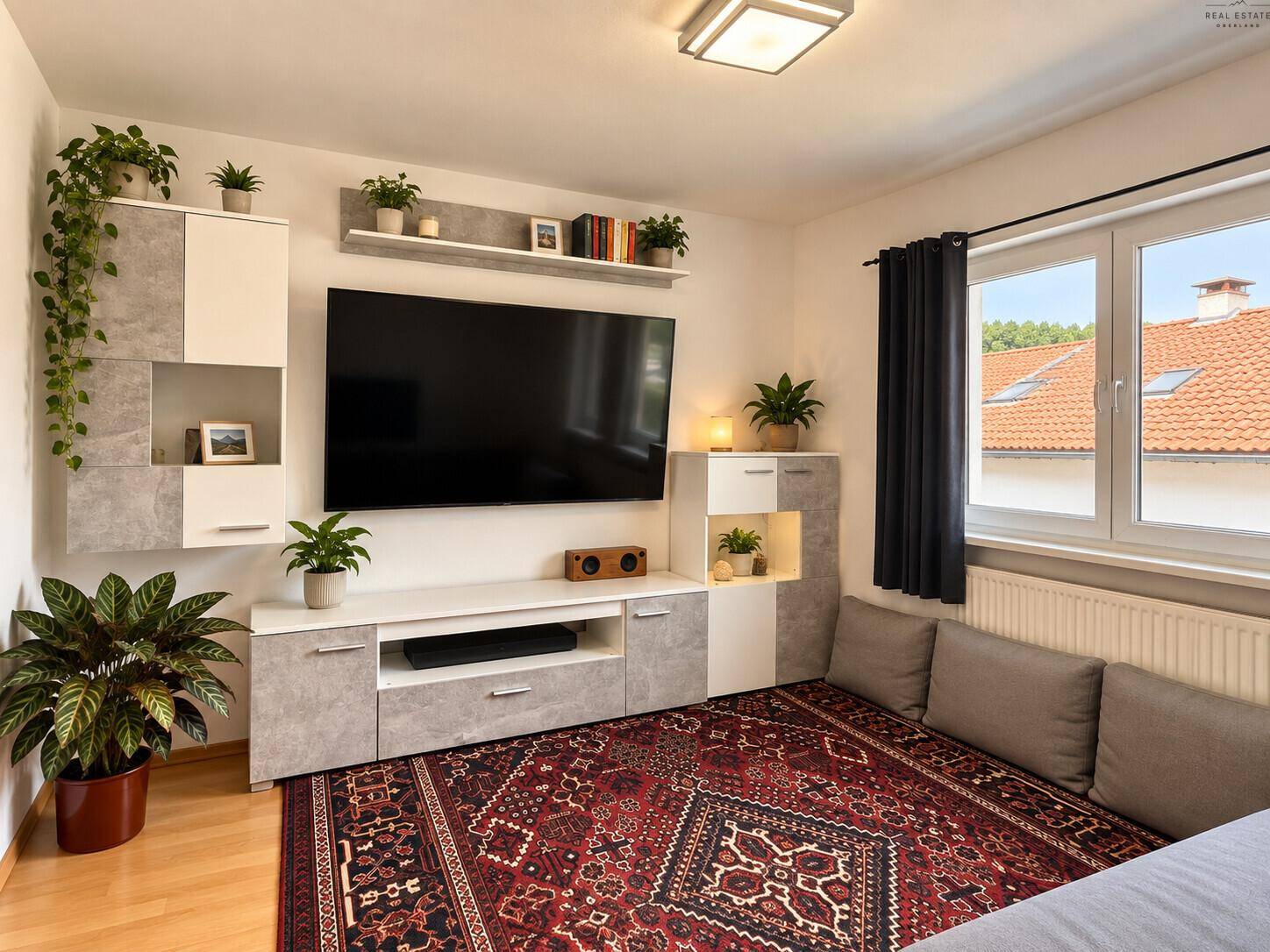 Wohnzimmer mit modernem Mediamöbel, Teppich und Blick auf die Dächer.