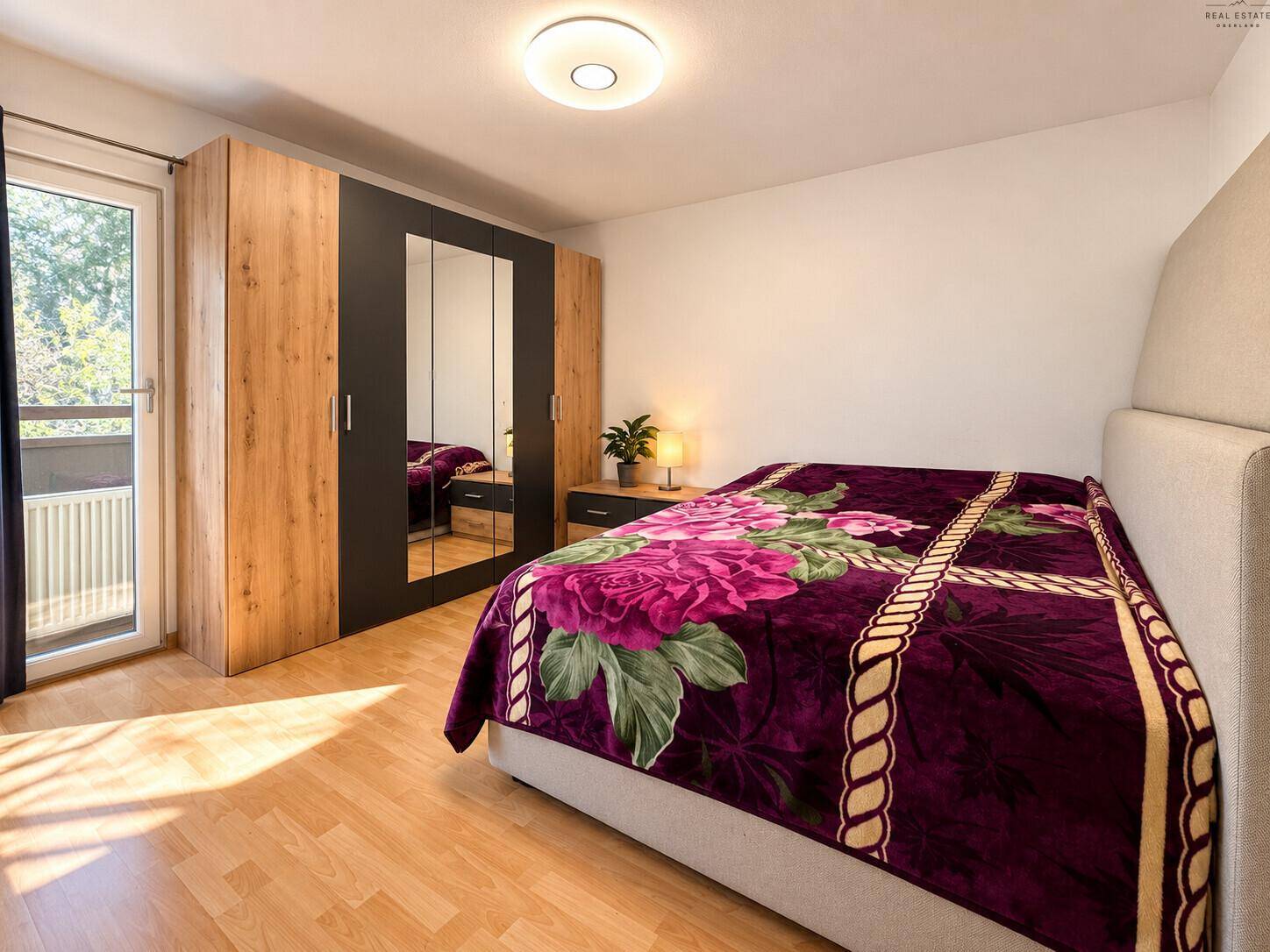 Schlafzimmer mit großem Kleiderschrank, Doppelbett und Balkonzugang.