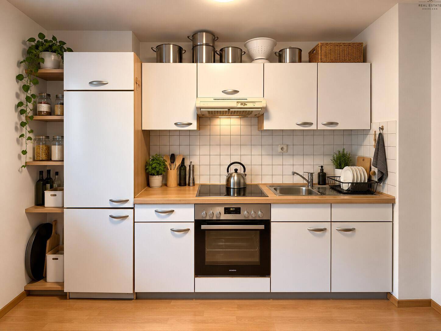 Moderne Einbauküche mit weißen Schränken, Holztheke und integrierten Geräten.