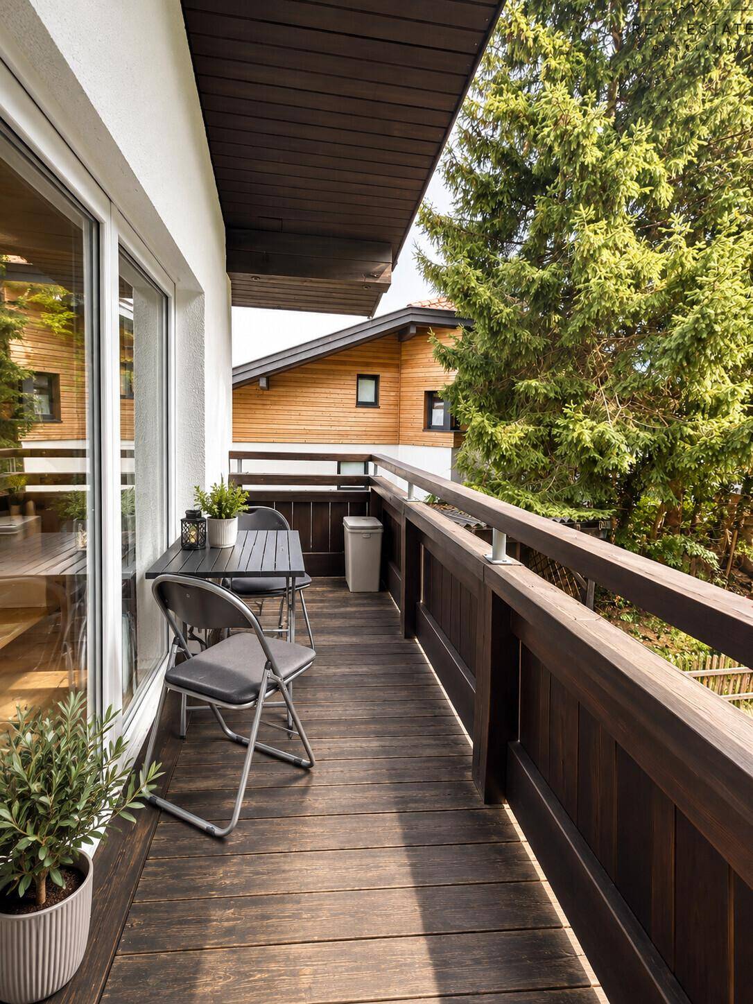 Holzverkleideter Balkon mit Sitzgelegenheiten und Blick auf die umliegende Natur.