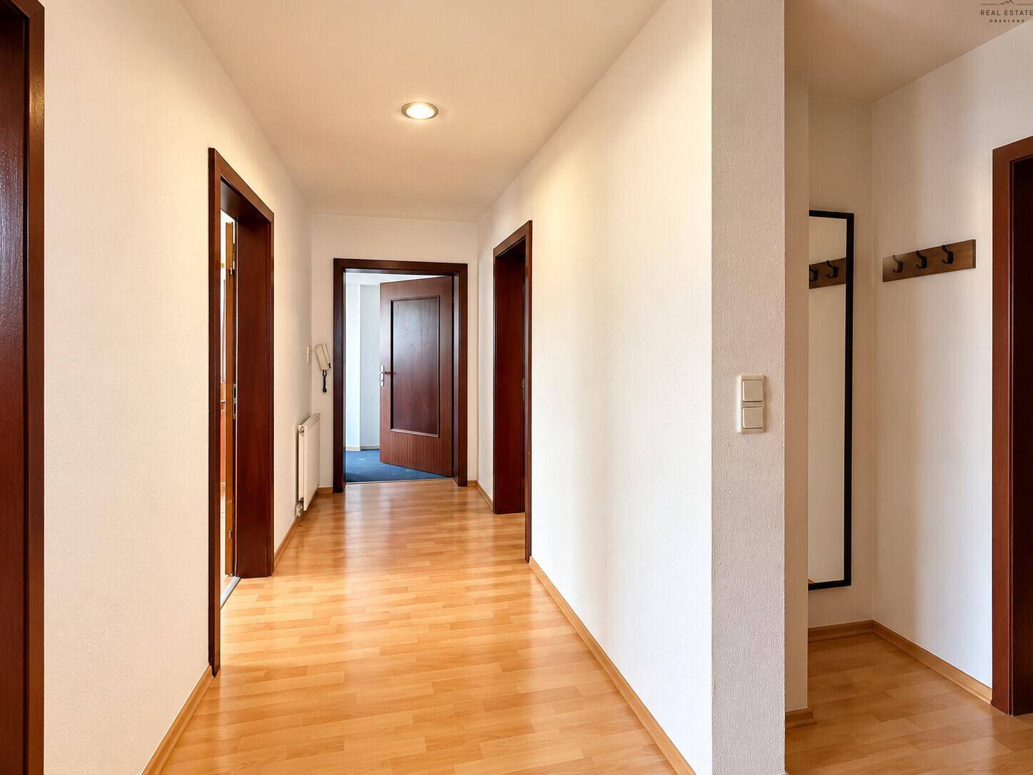Heller Flur mit Laminatboden und mehreren Holztüren.