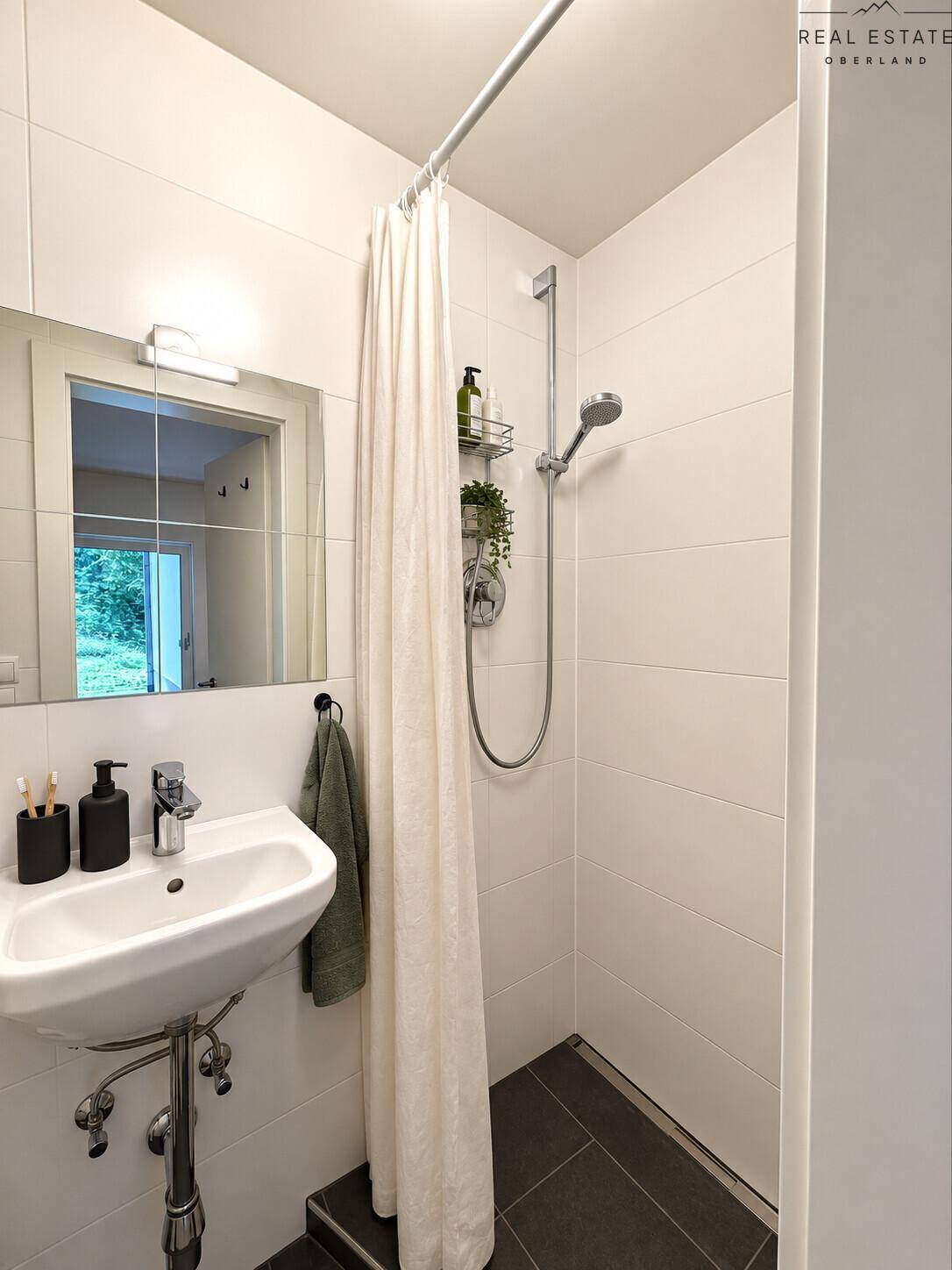 Modernes Badezimmer mit weiß gefliesten Wänden, Dusche und Einzelwaschbecken.