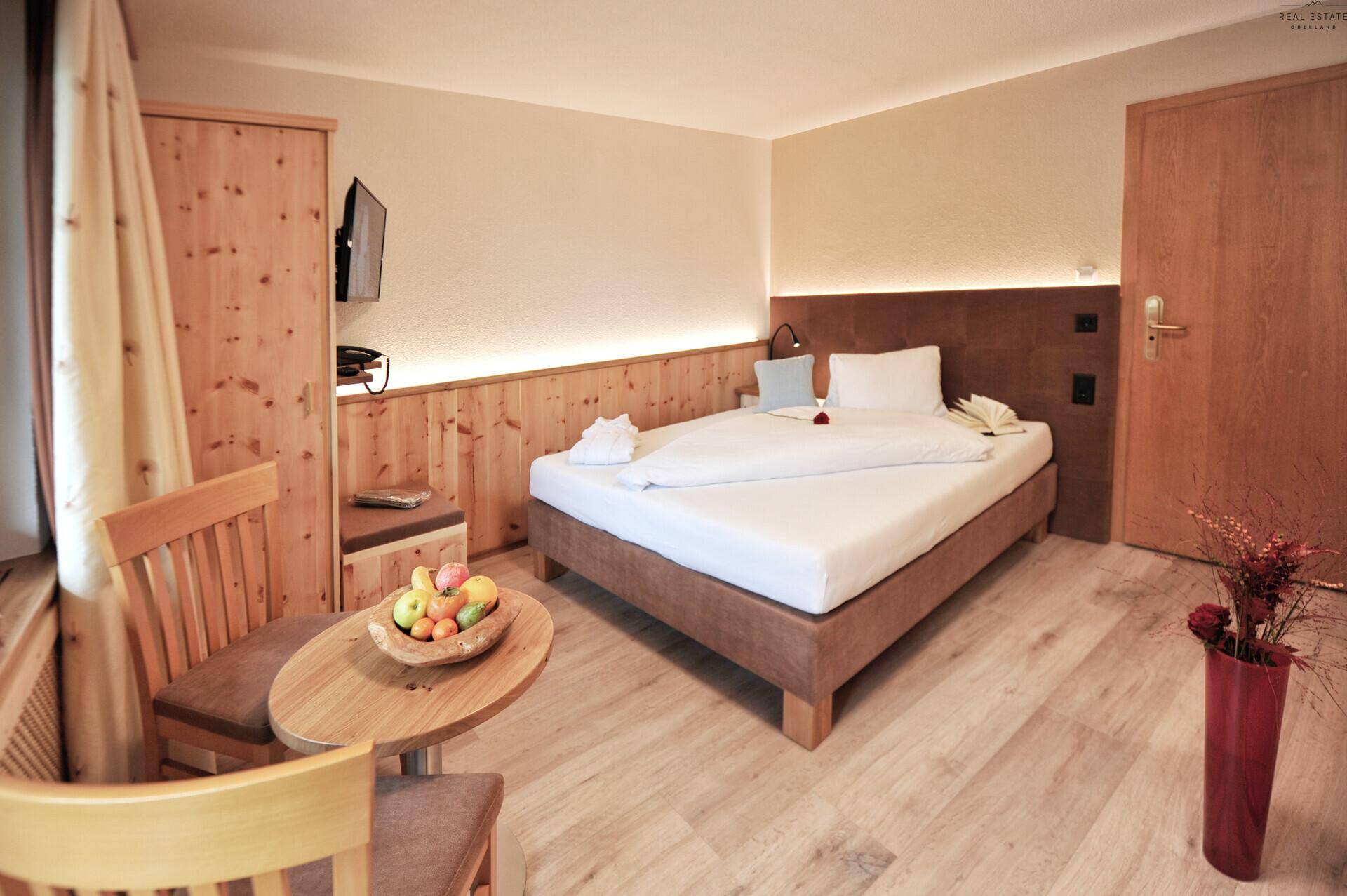 Schlafzimmer mit Doppelbett, Holzwandverkleidung und einem kleinen Tisch mit Stühlen.