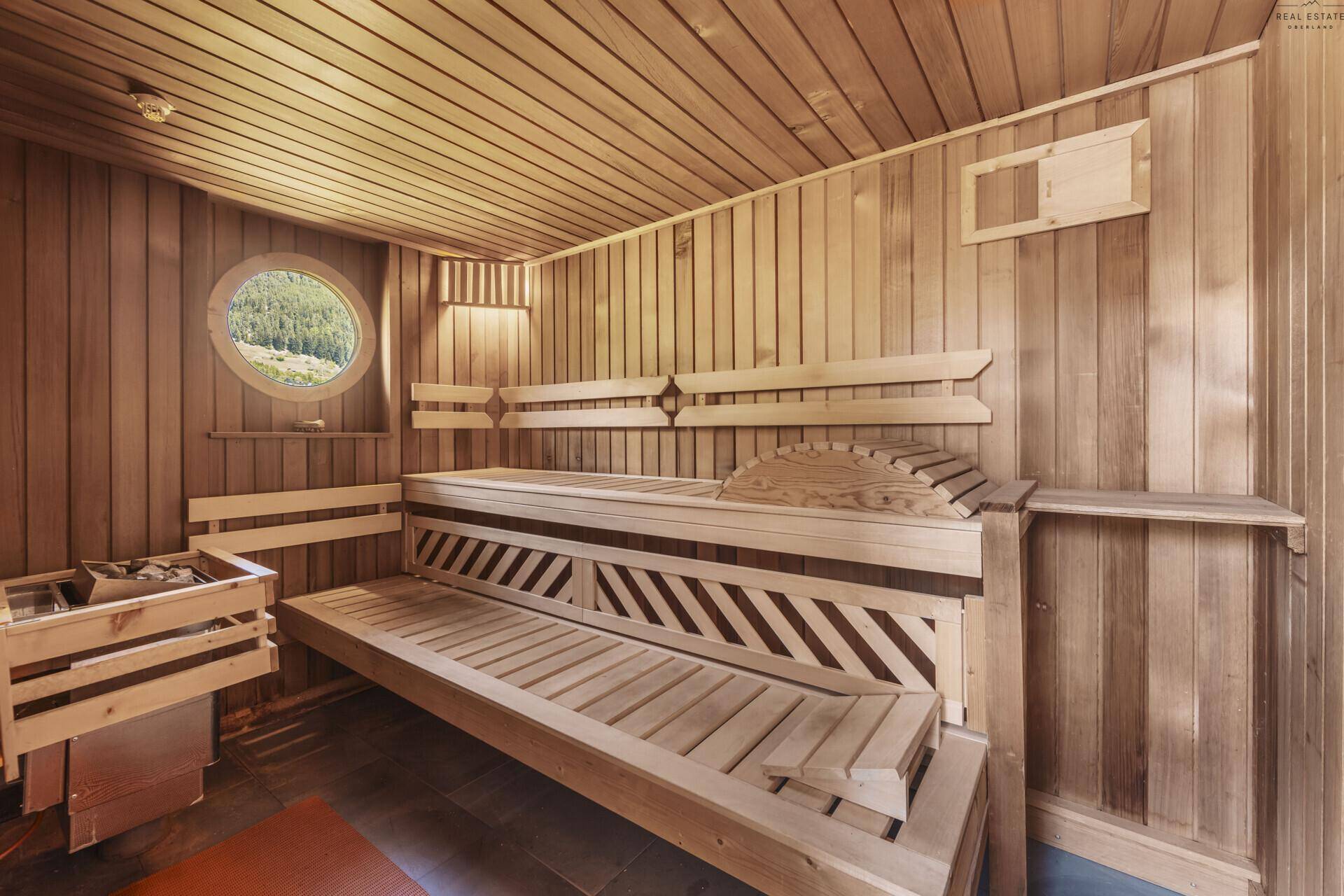 Traditionelle Holzsauna mit Sitzbänken und kleinem Fenster mit Blick ins Grüne.