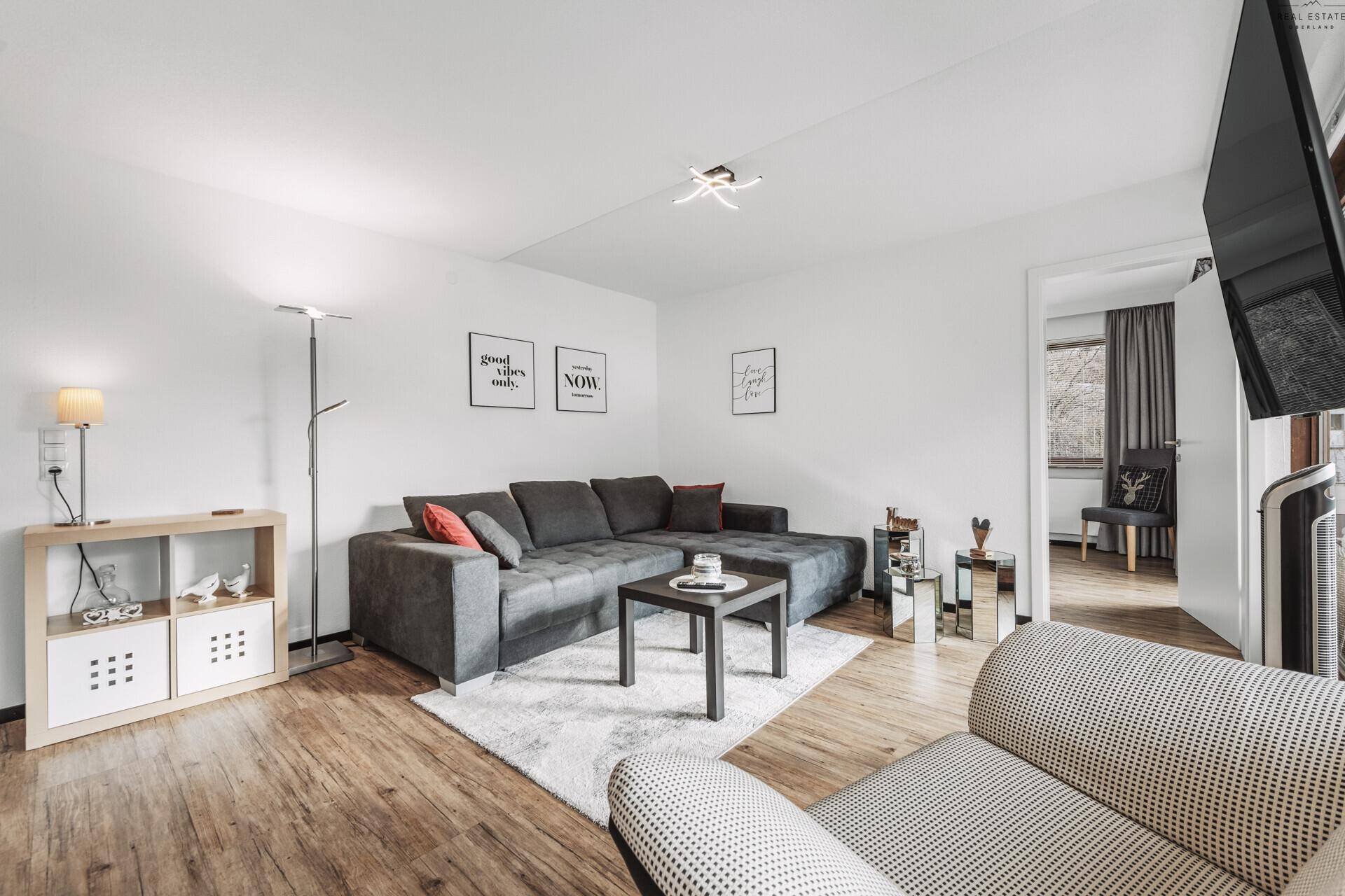 Gemütliches Wohnzimmer mit großem Ecksofa, Holzboden und moderner Dekoration.