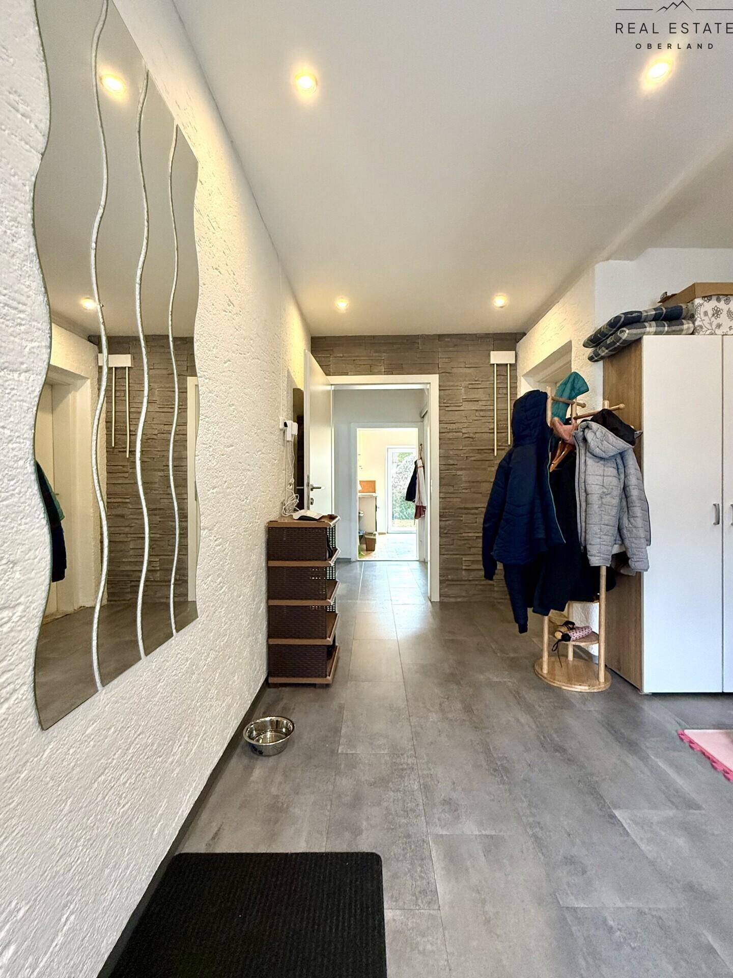 Heller Flur mit dekorativem Spiegel, Garderobe und modernem Fliesenboden.