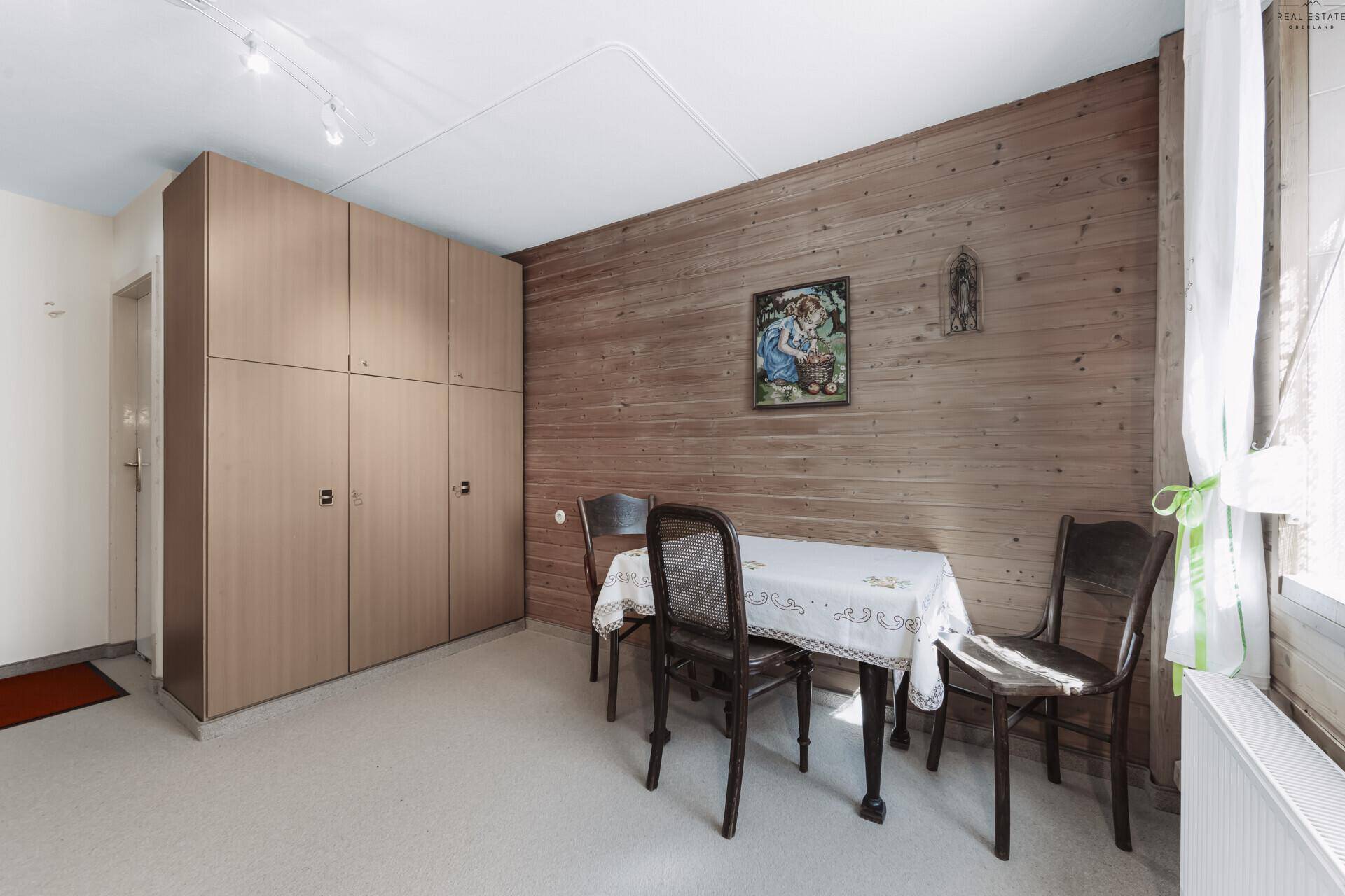 Schlafzimmer mit Holzwandverkleidung, Esstisch und großem Einbauschrank.