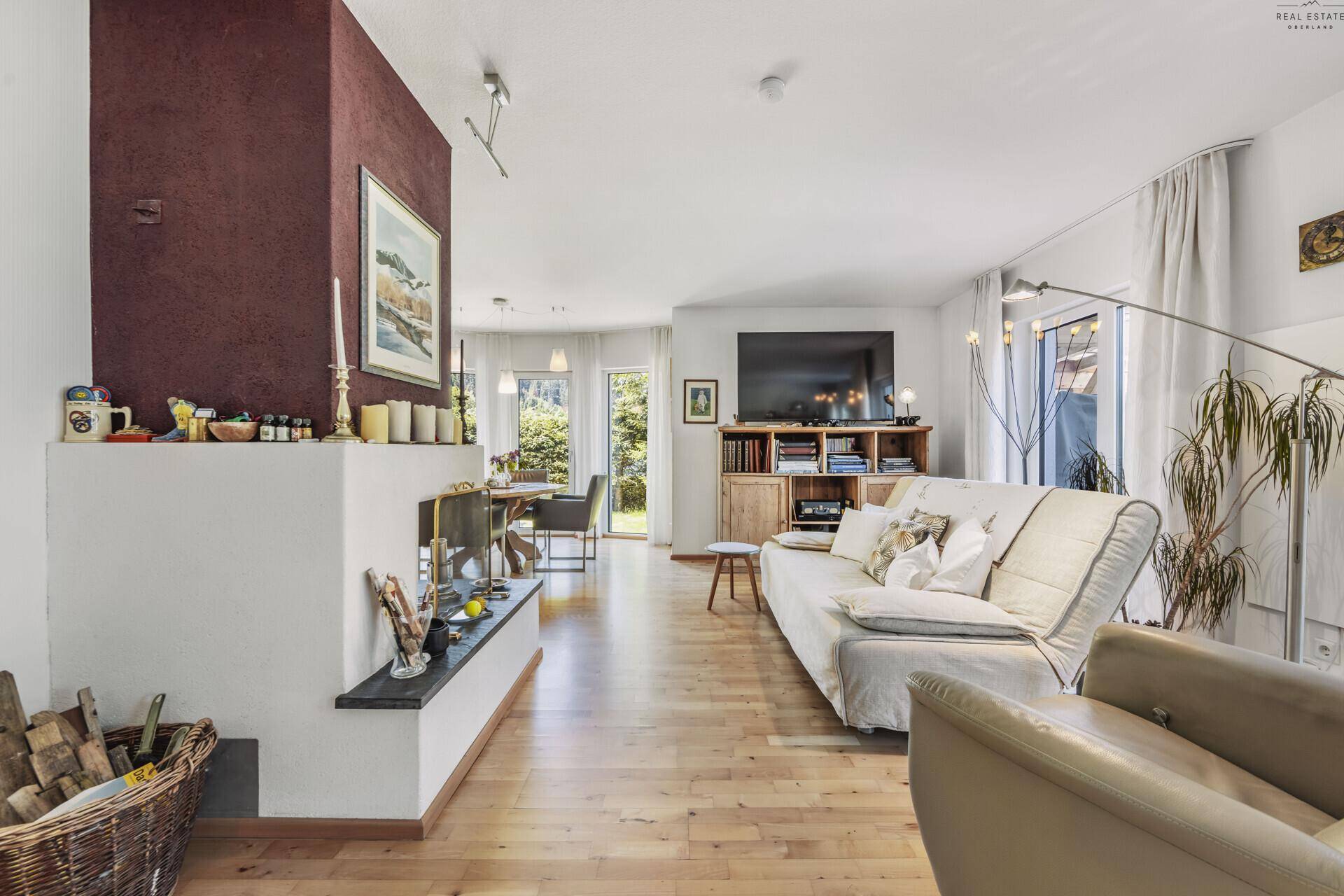 Geräumiges Wohnzimmer mit Kamin, Holzboden und Blick auf den Essbereich und die Küche.