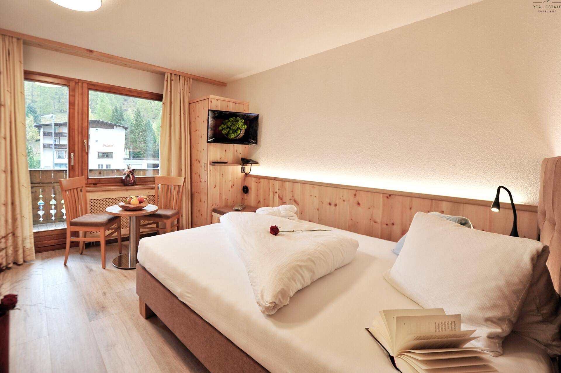 Schlafzimmer mit Doppelbett, Holzakzenten und Balkonzugang mit Bergblick.