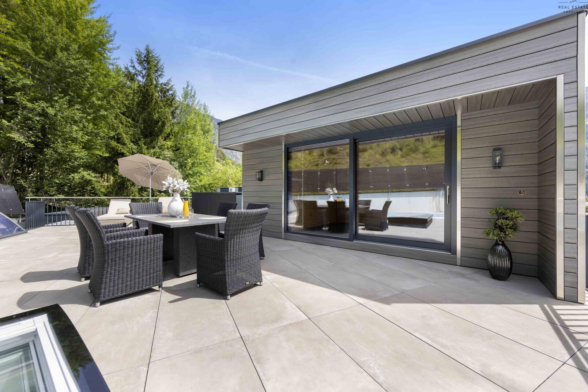Elegante Terrasse mit Essgruppe und großen Schiebetüren, die den Innenraum mit der Natur verbinden.