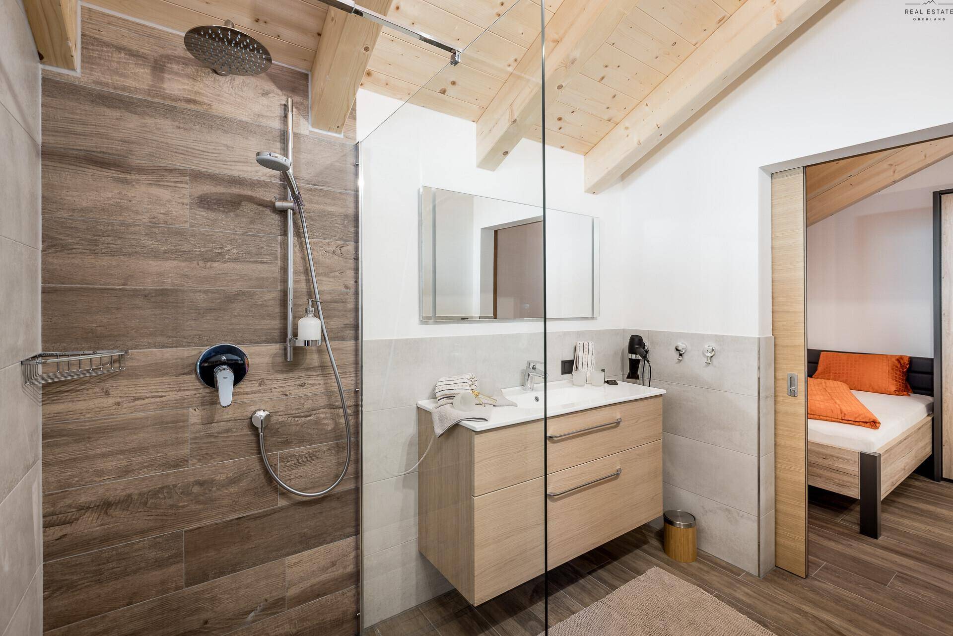 Modernes Badezimmer mit begehbarer Dusche, Holzoptikfliesen und Waschtisch.