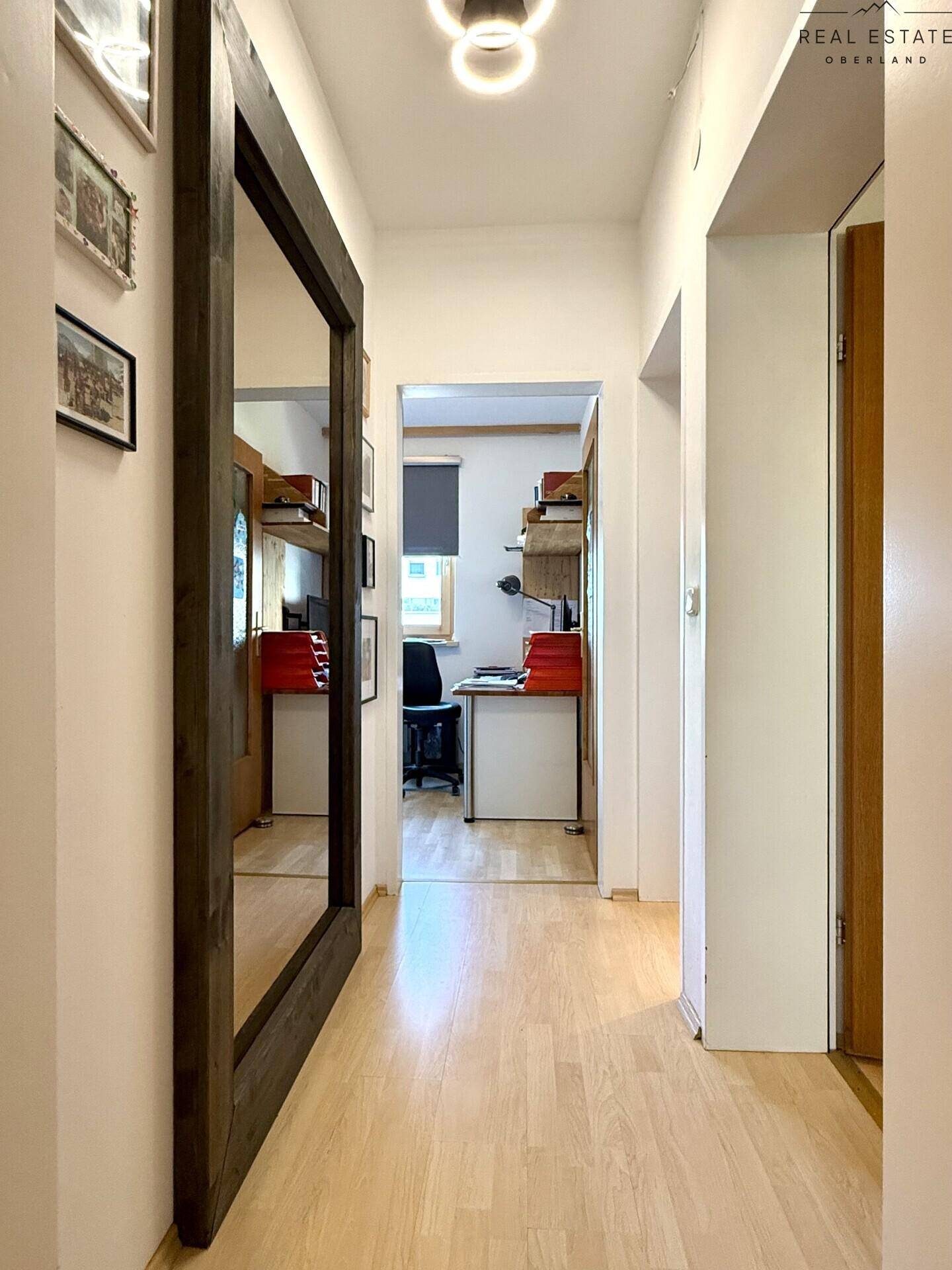 Heller Flur mit Holzboden und Blick in ein angrenzendes Arbeitszimmer.