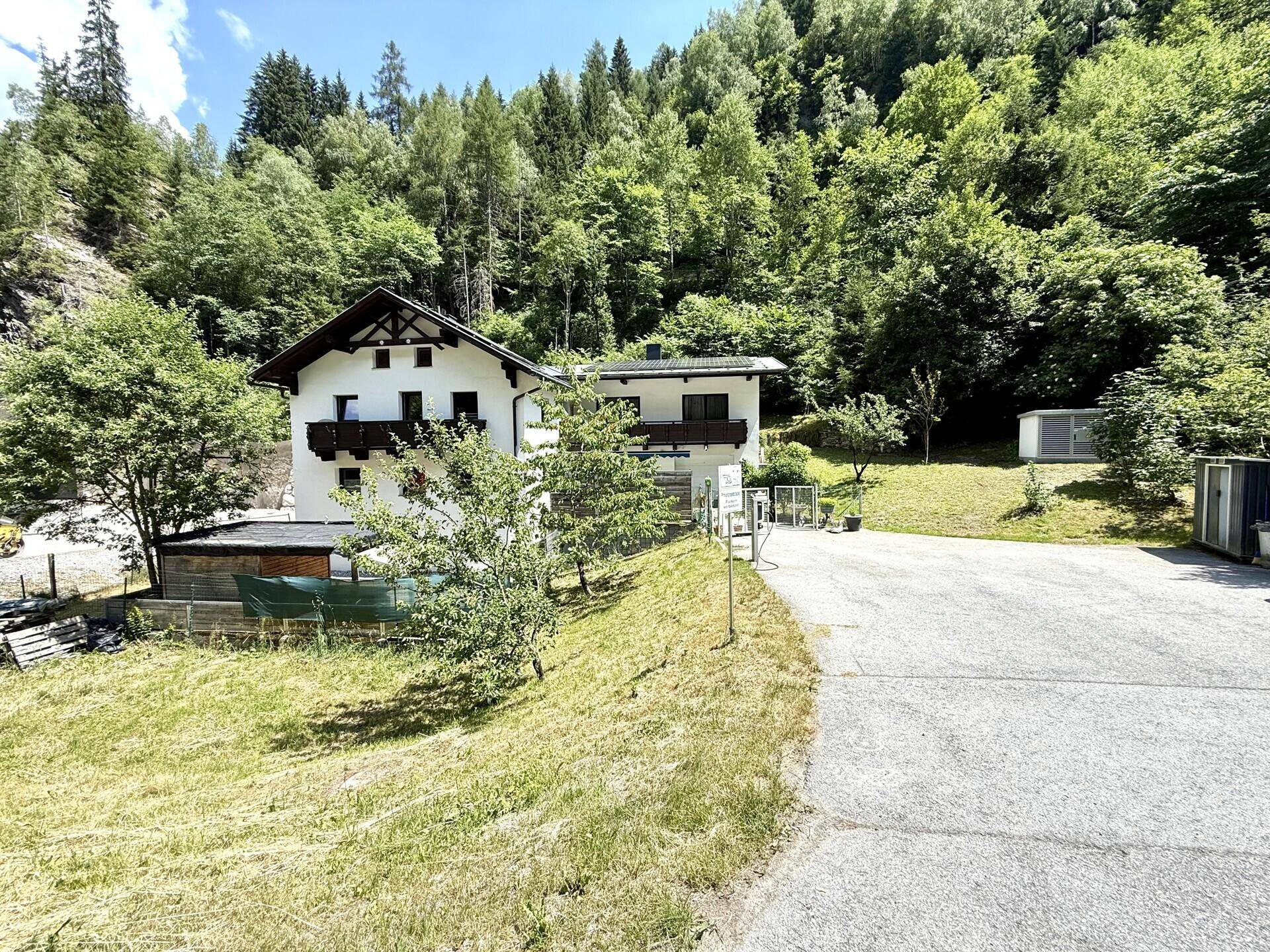 Freistehendes Haus in alpiner Umgebung mit weitem Blick auf die bewaldeten Berghänge.
