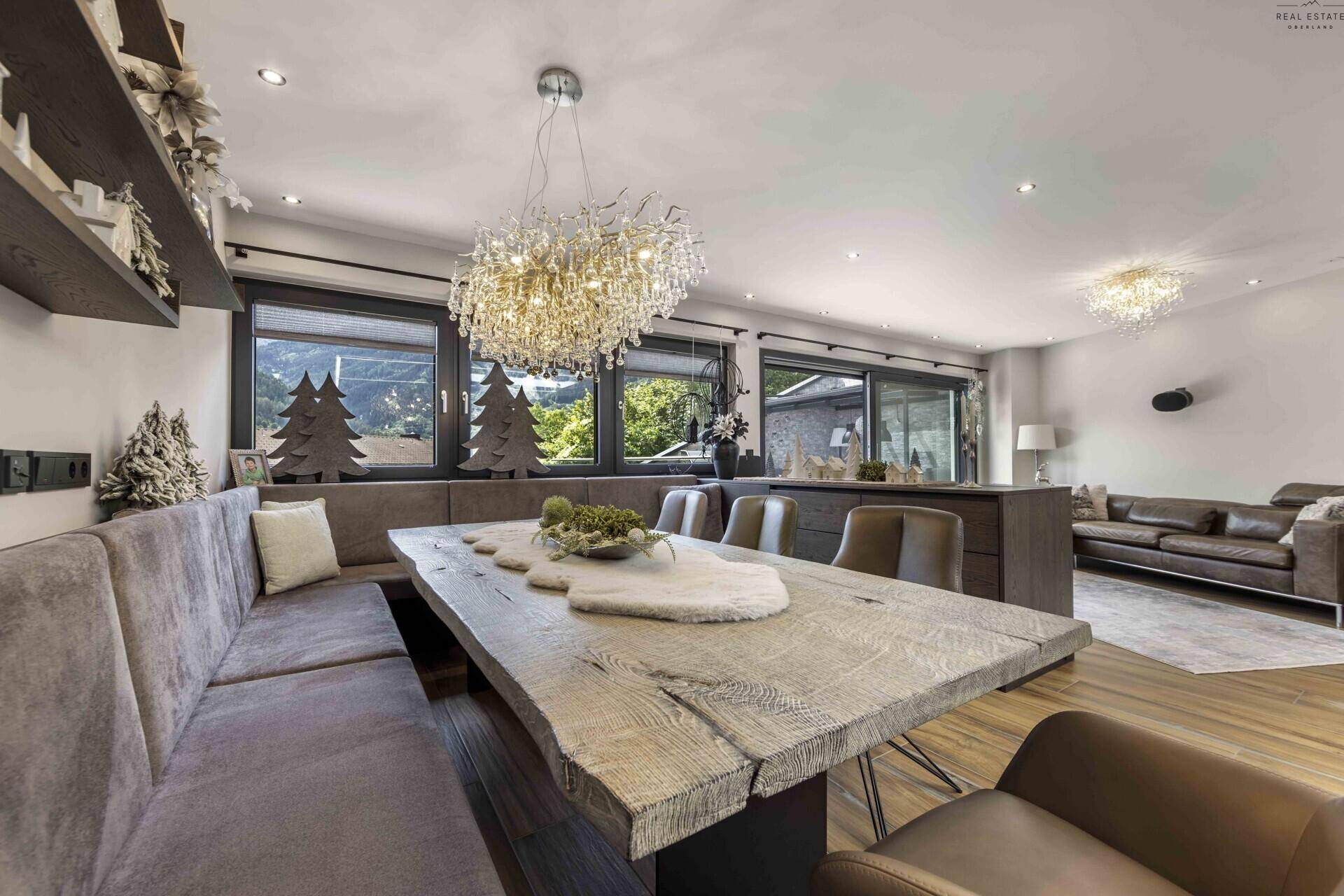 Geräumiger Essbereich mit massivem Holztisch, bequemer Sitzbank und elegantem Kronleuchter.