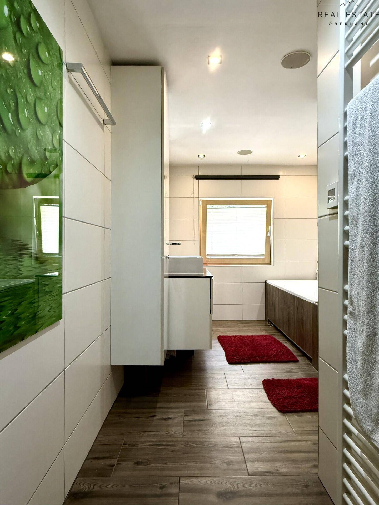 Helles Badezimmer mit Badewanne, Dusche und Fenster, modern gefliest und gut beleuchtet.