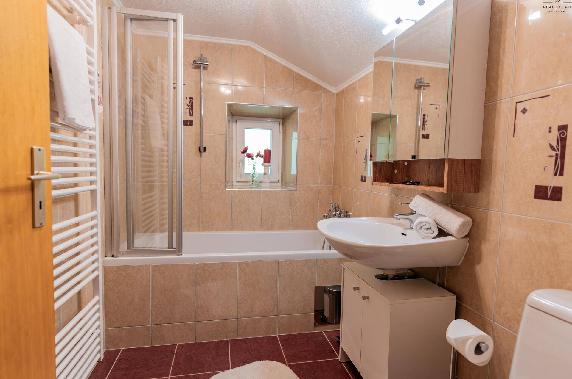 Badezimmer mit Badewanne, Duschabtrennung, WC und beheiztem Handtuchhalter.