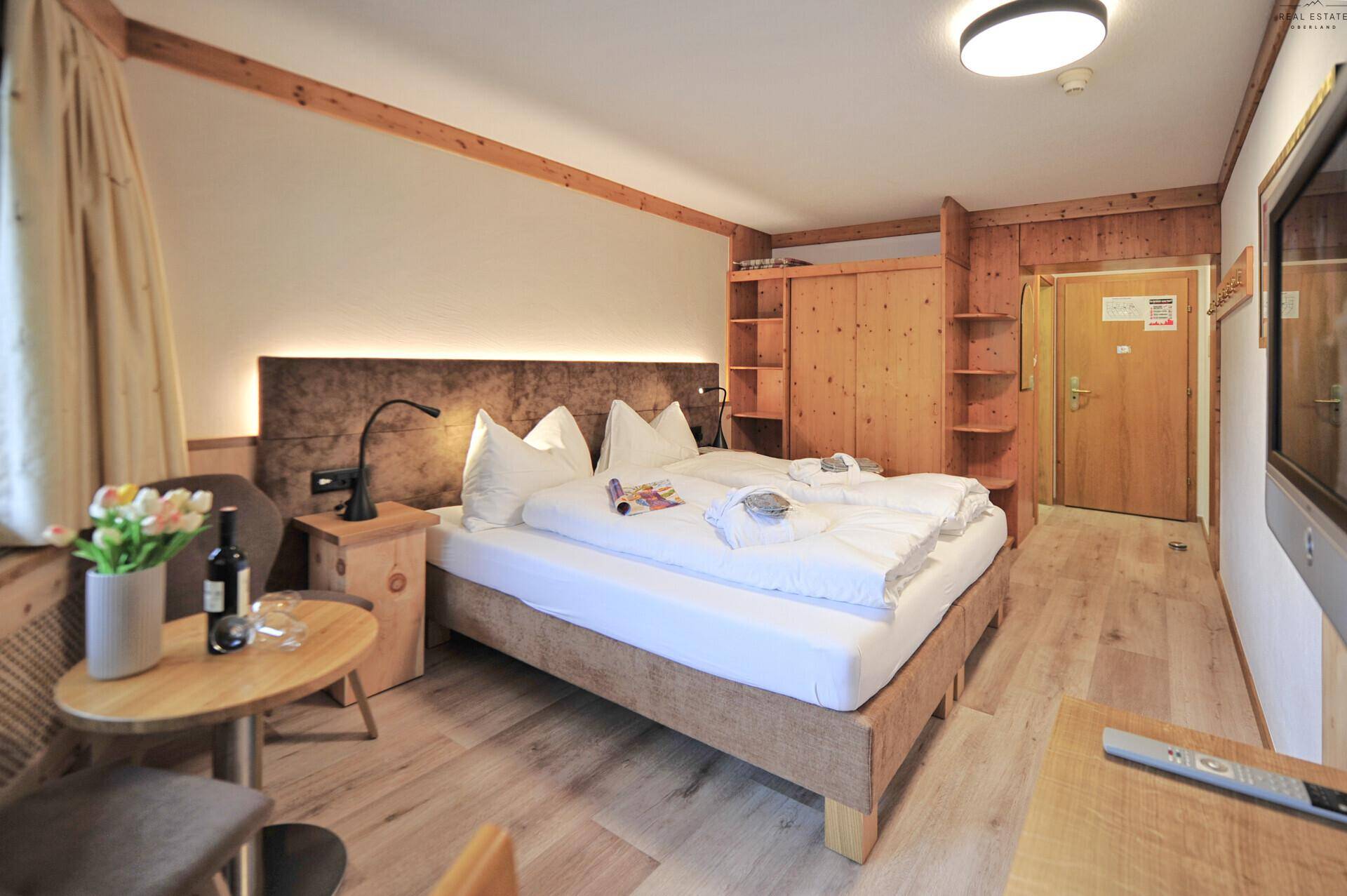 Schlafzimmer mit Doppelbett, integriertem Kleiderschrank und einem an der Wand befestigten Fernseher.
