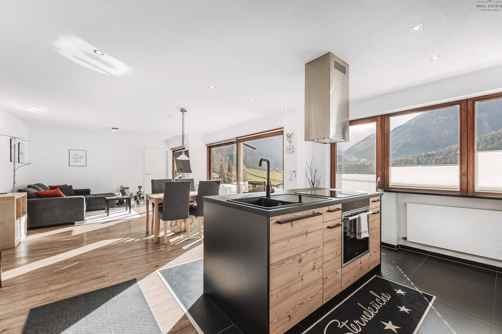 Offene Küche mit moderner Insel, integrierten Geräten und direktem Blick auf die Berge.