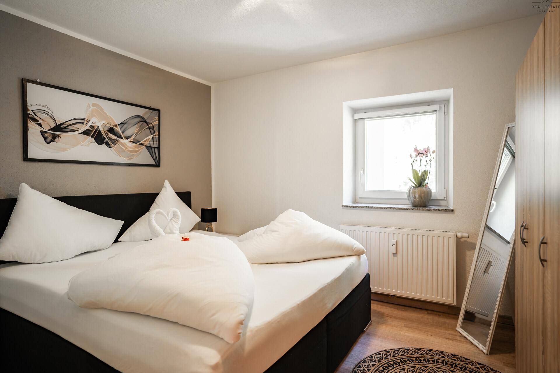 Schlafzimmer mit Doppelbett, Nachttischen und Fenster für natürliches Licht.