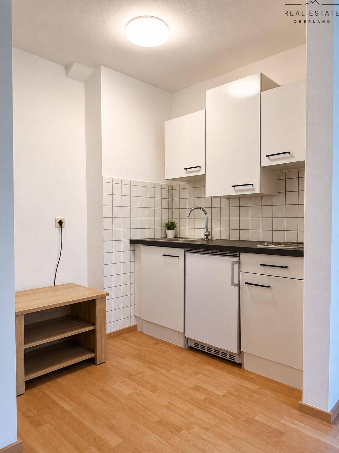 Funktionale Küchenzeile mit weißen Schränken, Spüle und integriertem Kühlschrank.