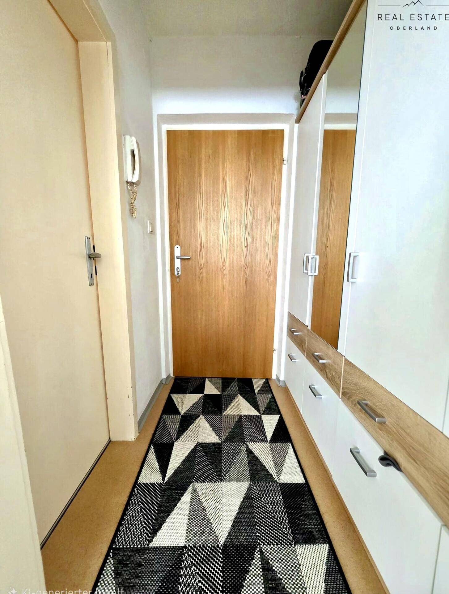 Heller Flur mit Holztür, weißem Einbauschrank und gemustertem Teppich.