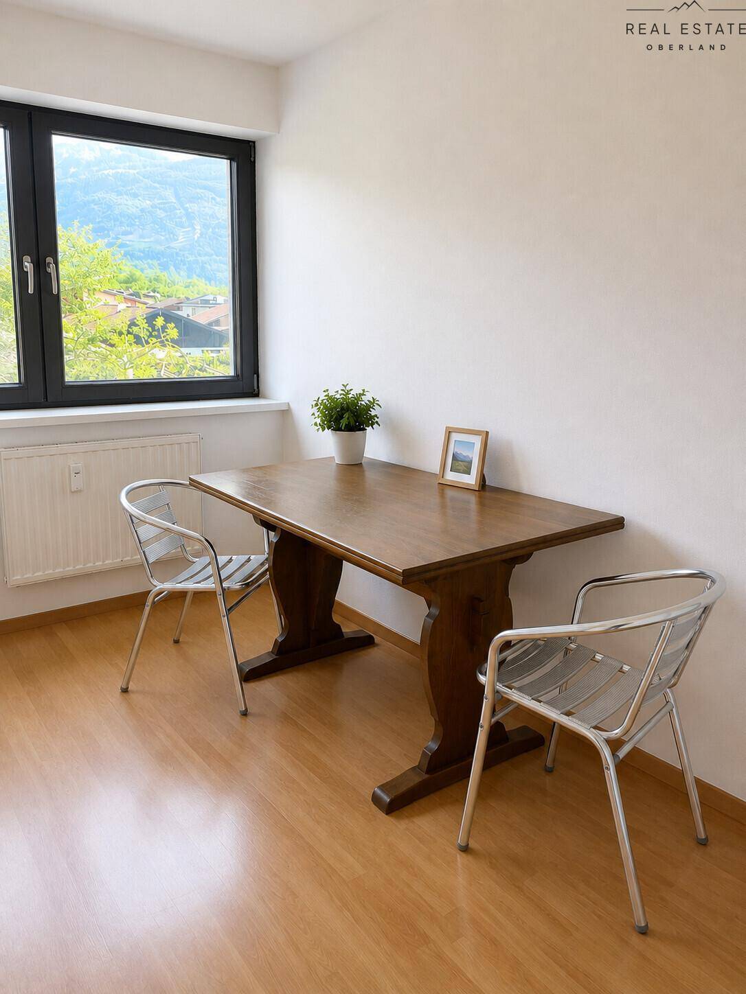 Essbereich mit Holztisch und Stühlen, bietet einen weiten Blick auf die Berge.