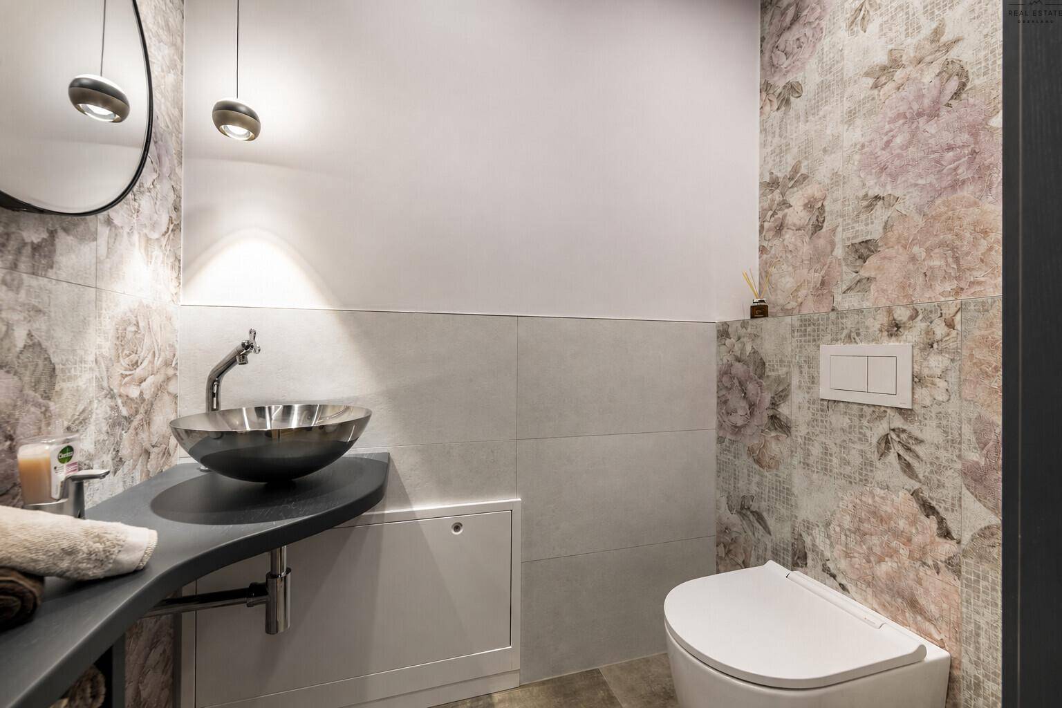 Modernes Gäste-WC mit floraler Tapete, stilvollem Waschbecken und wandhängendem WC.