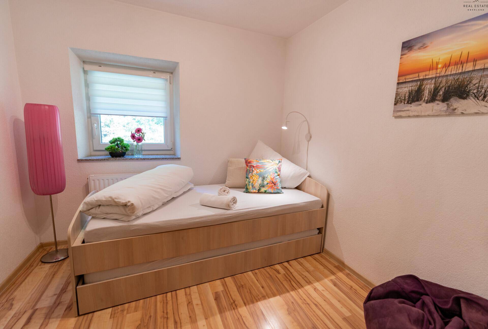 Helles Schlafzimmer mit Einzelbett, Fenster und Holzboden, ideal für Gäste.