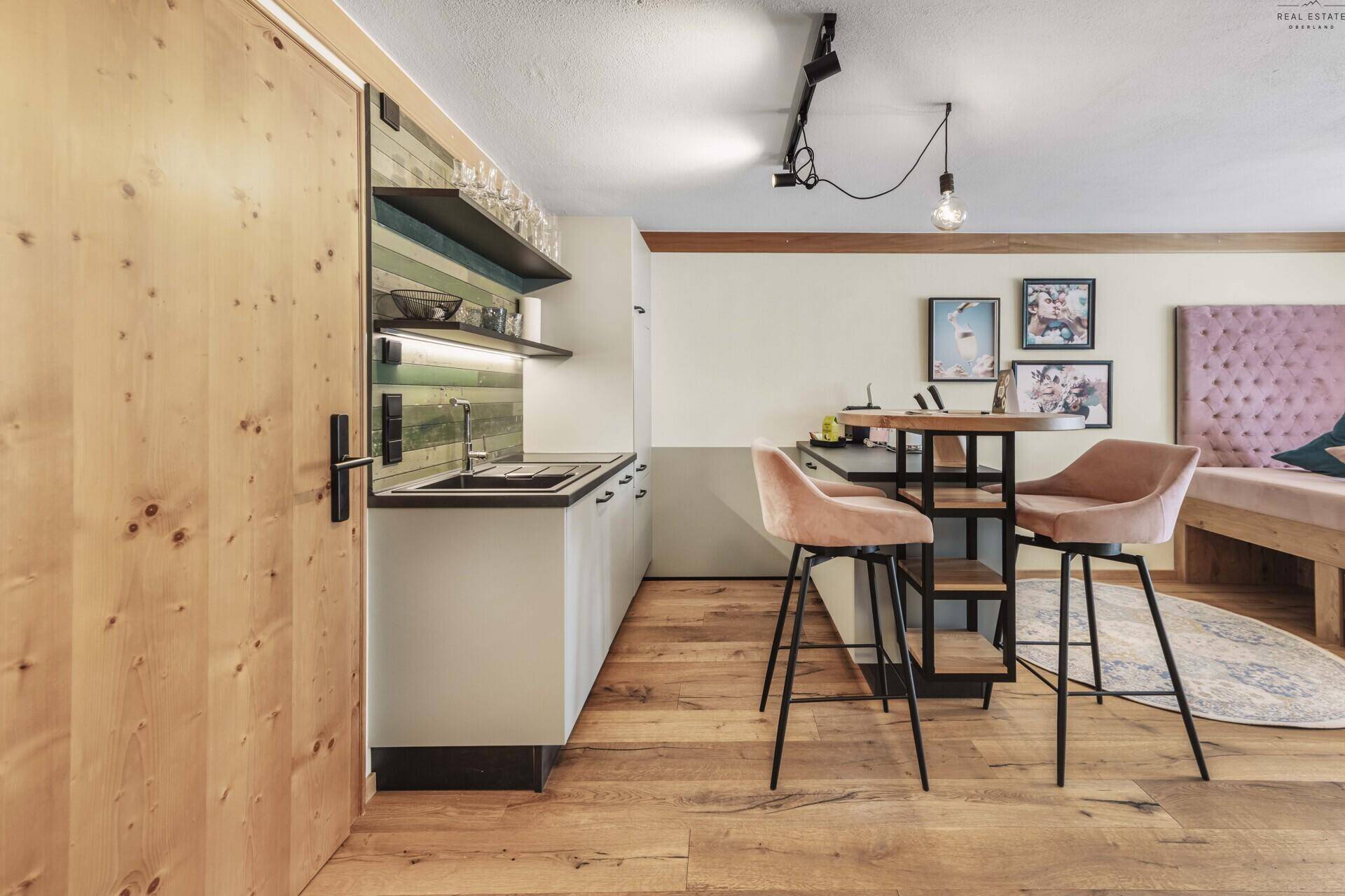 Funktionale Küchenzeile in einem Studio-Apartment mit Bartisch und Holzfußboden.