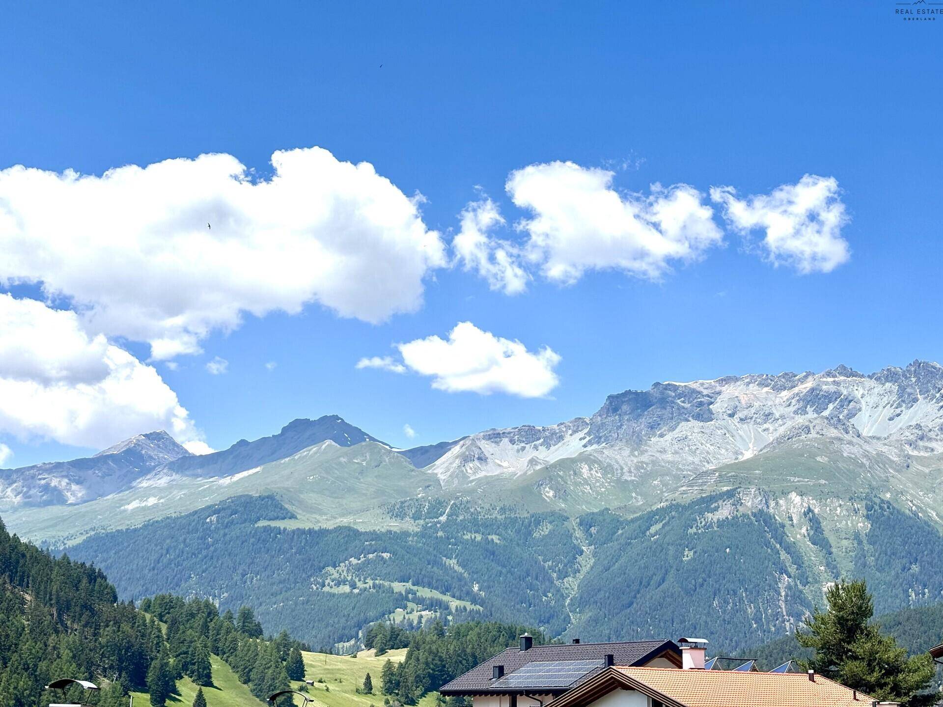 Panoramablick auf die majestätischen Berge und grüne Täler unter blauem Himmel.