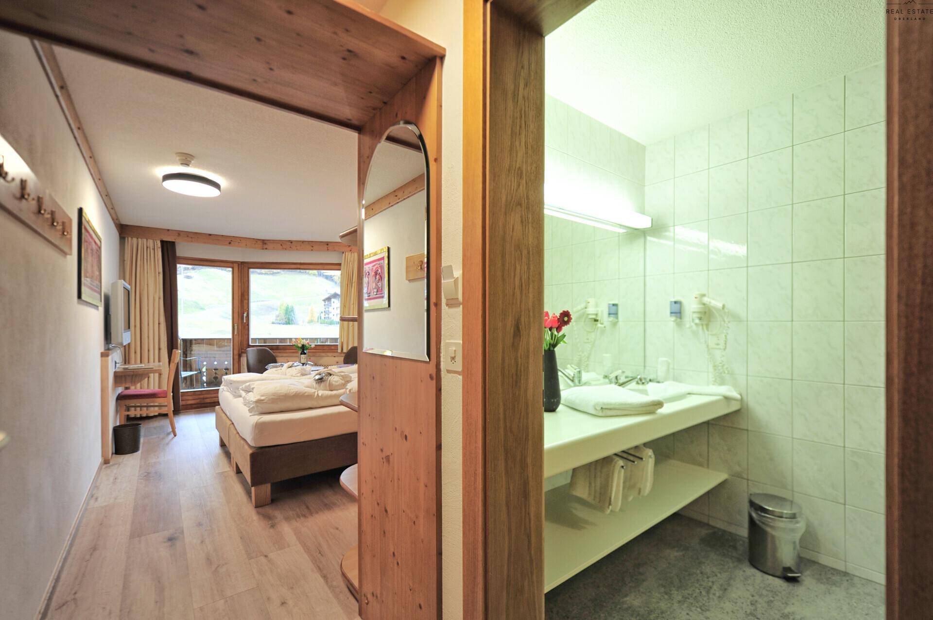 Blick vom Flur in ein Schlafzimmer mit Balkonzugang und ein angrenzendes Badezimmer.