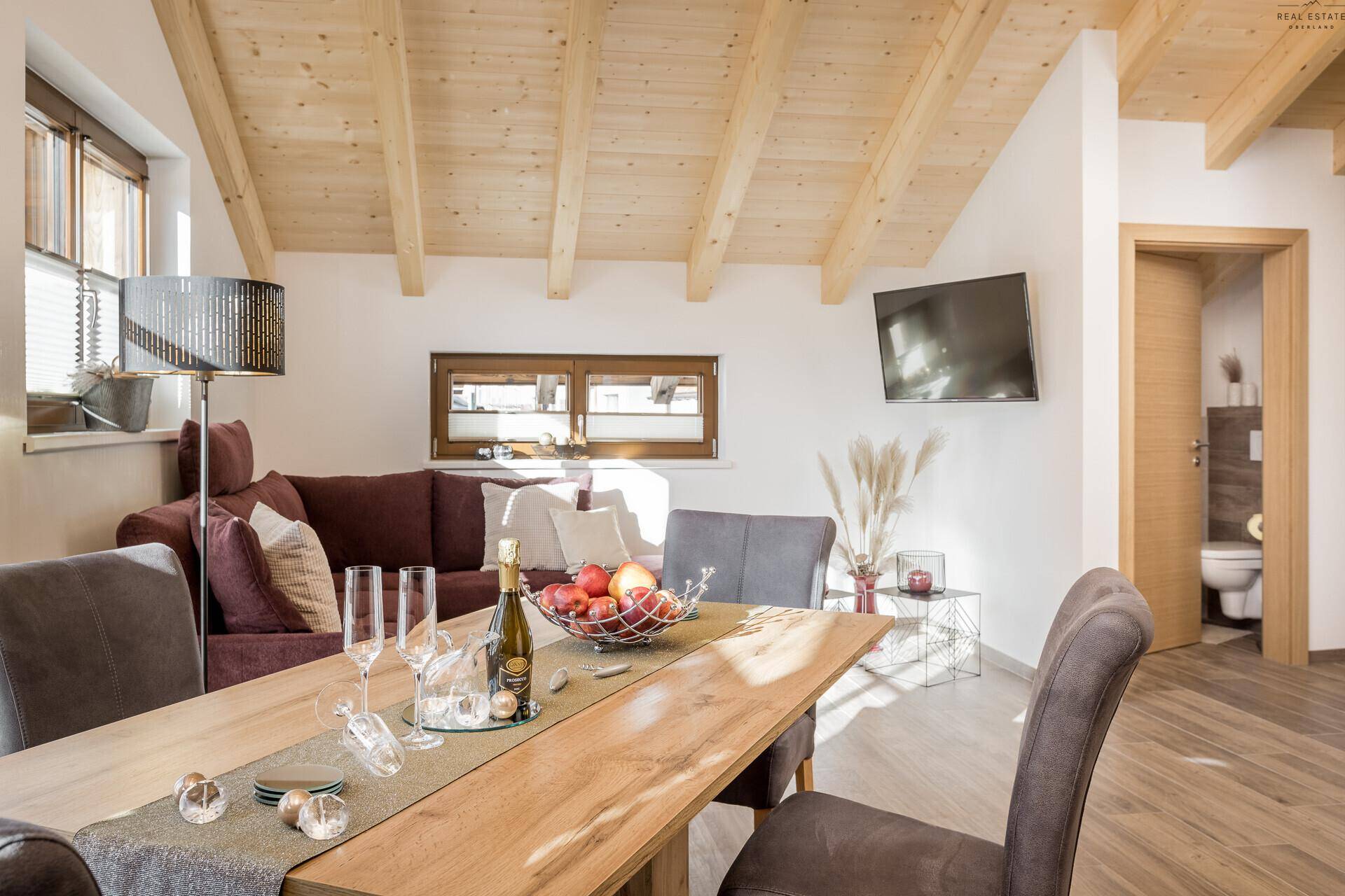 Heller Wohn-Essbereich mit Holzbalkendecke, gemütlichem Sofa und Blick auf den Flur.