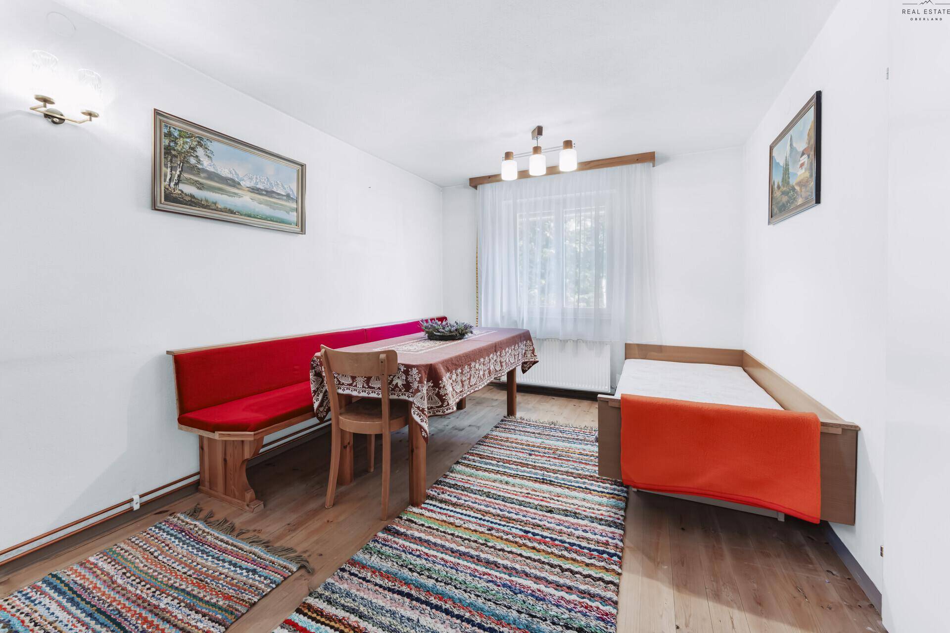 Essbereich mit traditioneller Eckbank und Tisch, ergänzt durch ein Einzelbett.