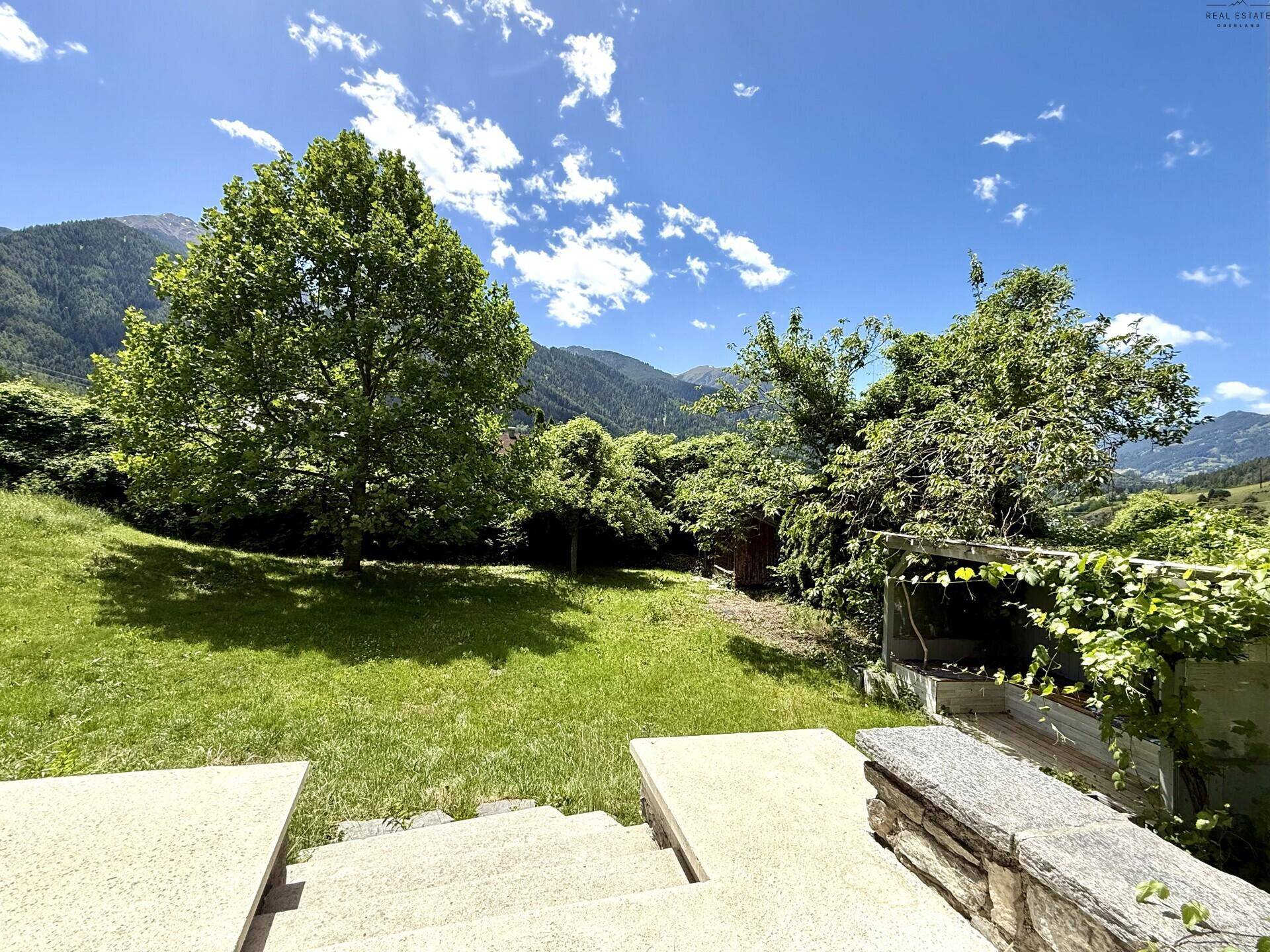 Weitläufiger Garten mit Rasen, Bäumen und einem kleinen Schuppen im Hintergrund.