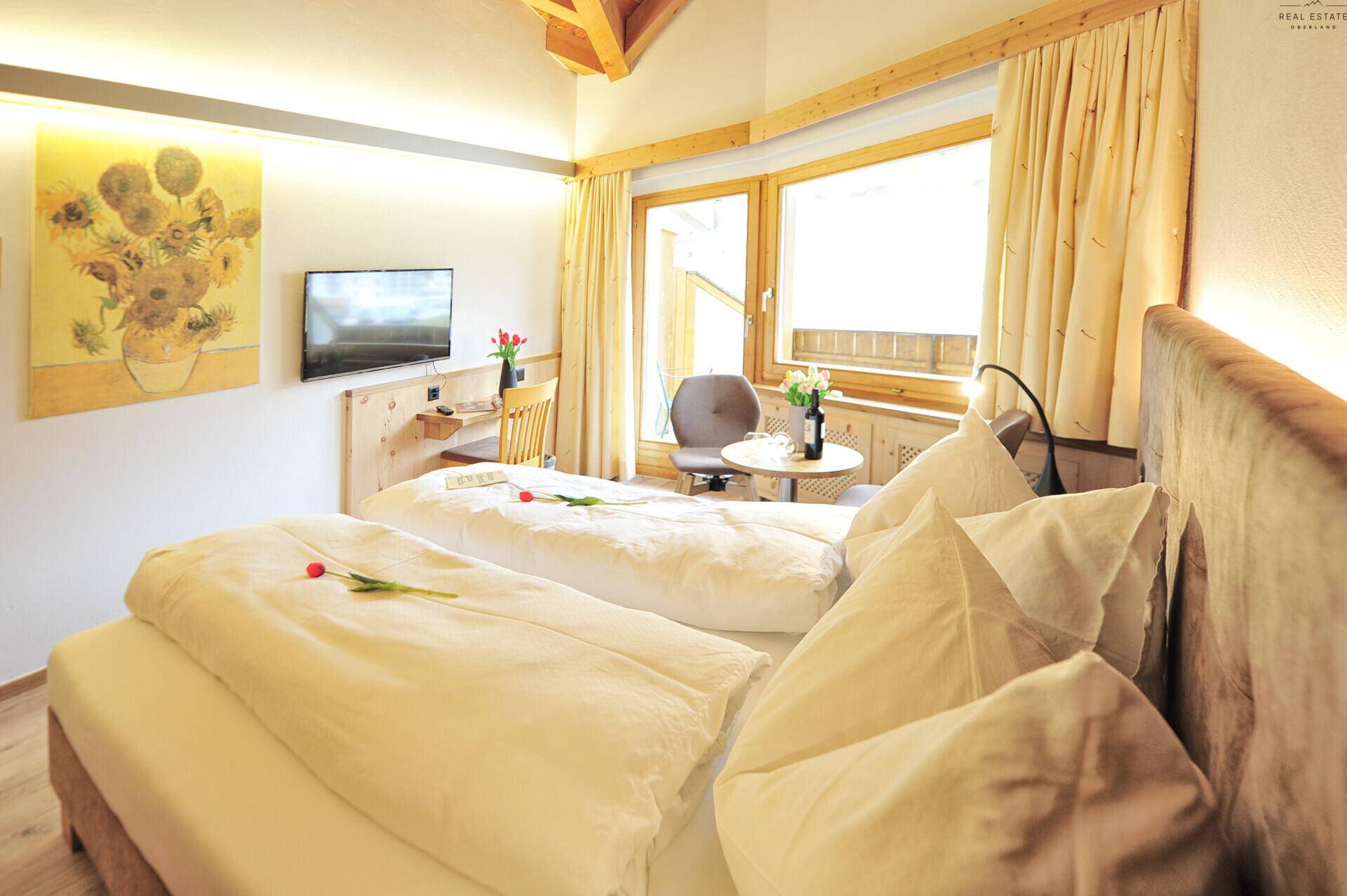 Gemütliches Schlafzimmer mit zwei Einzelbetten, Holzakzenten, Dachschräge und Blick ins Grüne.