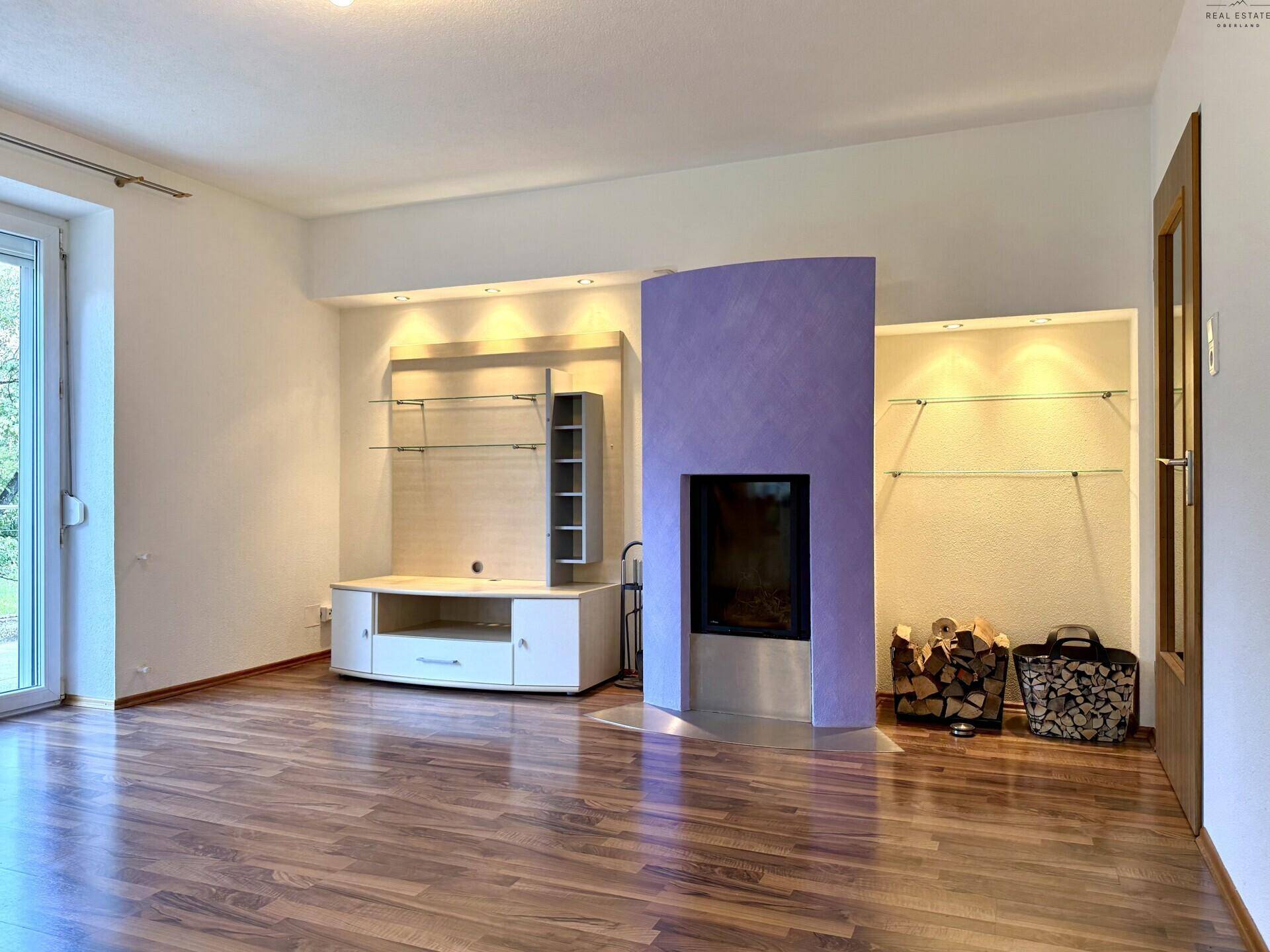 Wohnzimmer mit Laminatboden, modernem Kamin und integriertem Medienmöbel in heller Farbgebung.